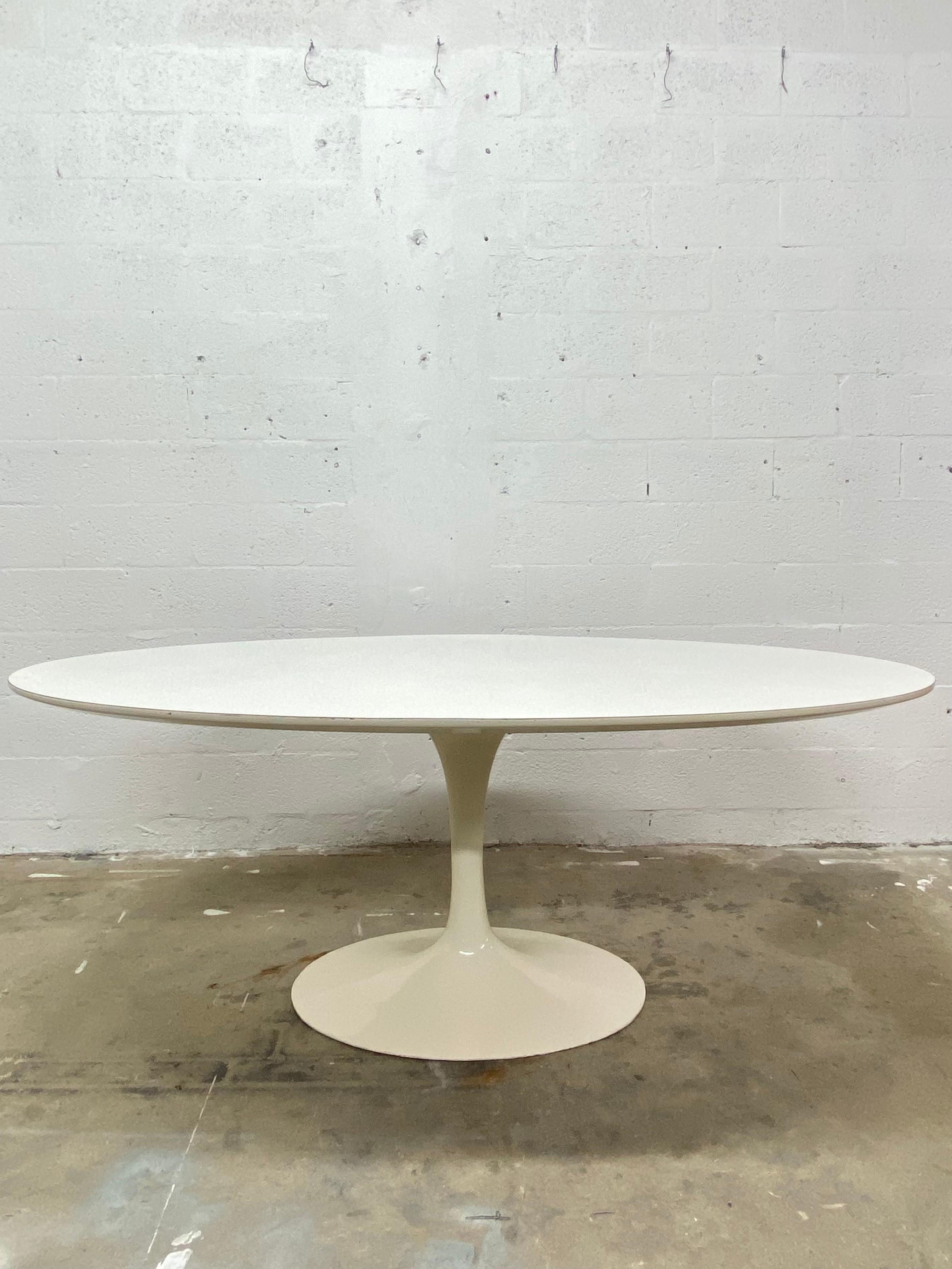 Rare, early edition 1960s Eero Saarinen white oval laminate top with lacquered cast iron base dining table produced by Knoll. Maintains original Knoll Associates label on underside.