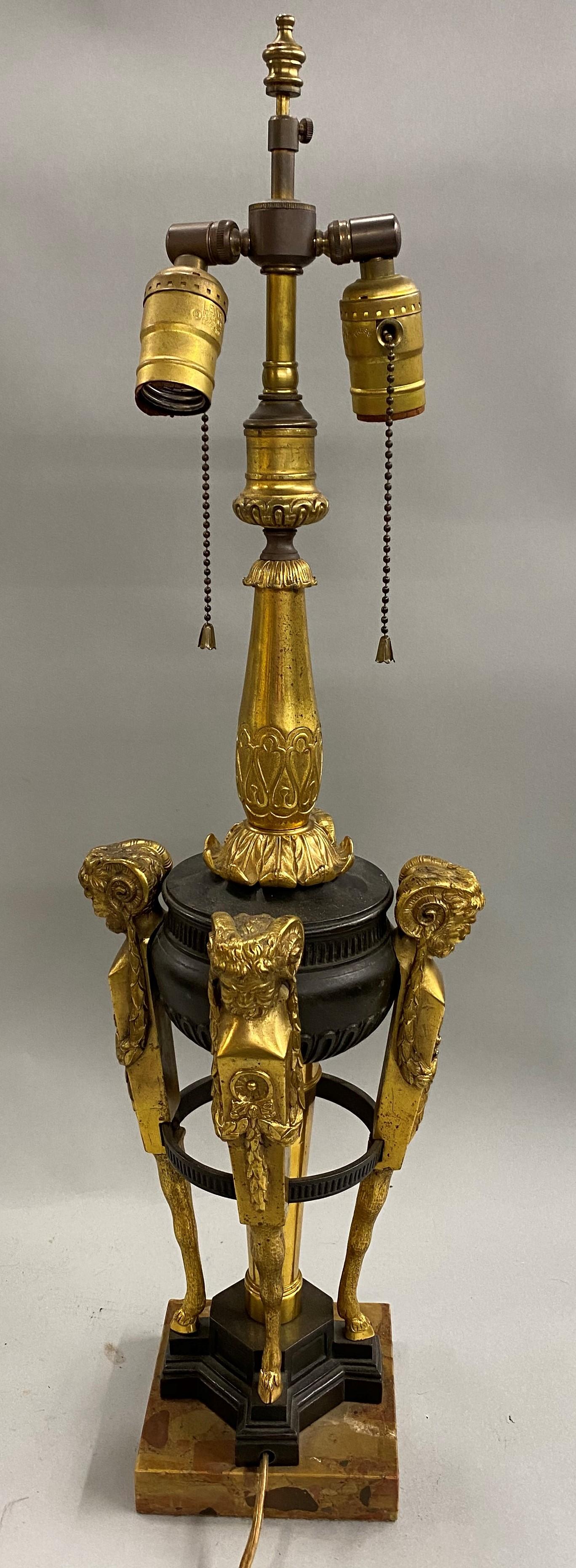 A fine quality EF Caldwell & Co bronze two light urn form table lamp with gilt foliate decorated stem and supported by four gilt bronze Bacchanalian figures with single hooves, all mounted on a marble base, unsigned, circa 1900, in very good overall