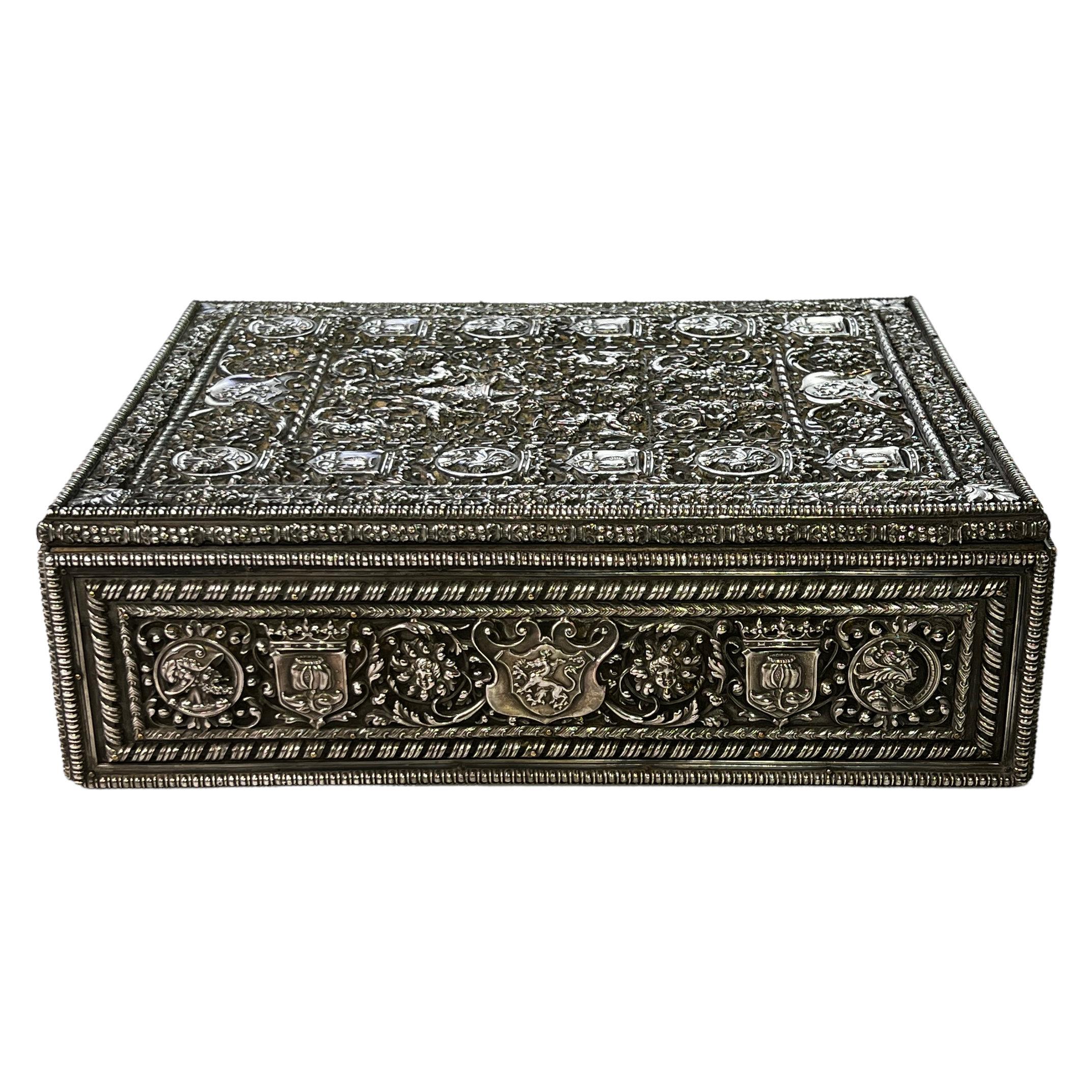 Our silvered-bronze and velvet humidor in the Renaissance fashion was produced by Edward F. Caldwell and Co., circa 1910. Its lid and sides feature elaborate pierced repossé decorations including scrolling foliage, armorials, masks and musician