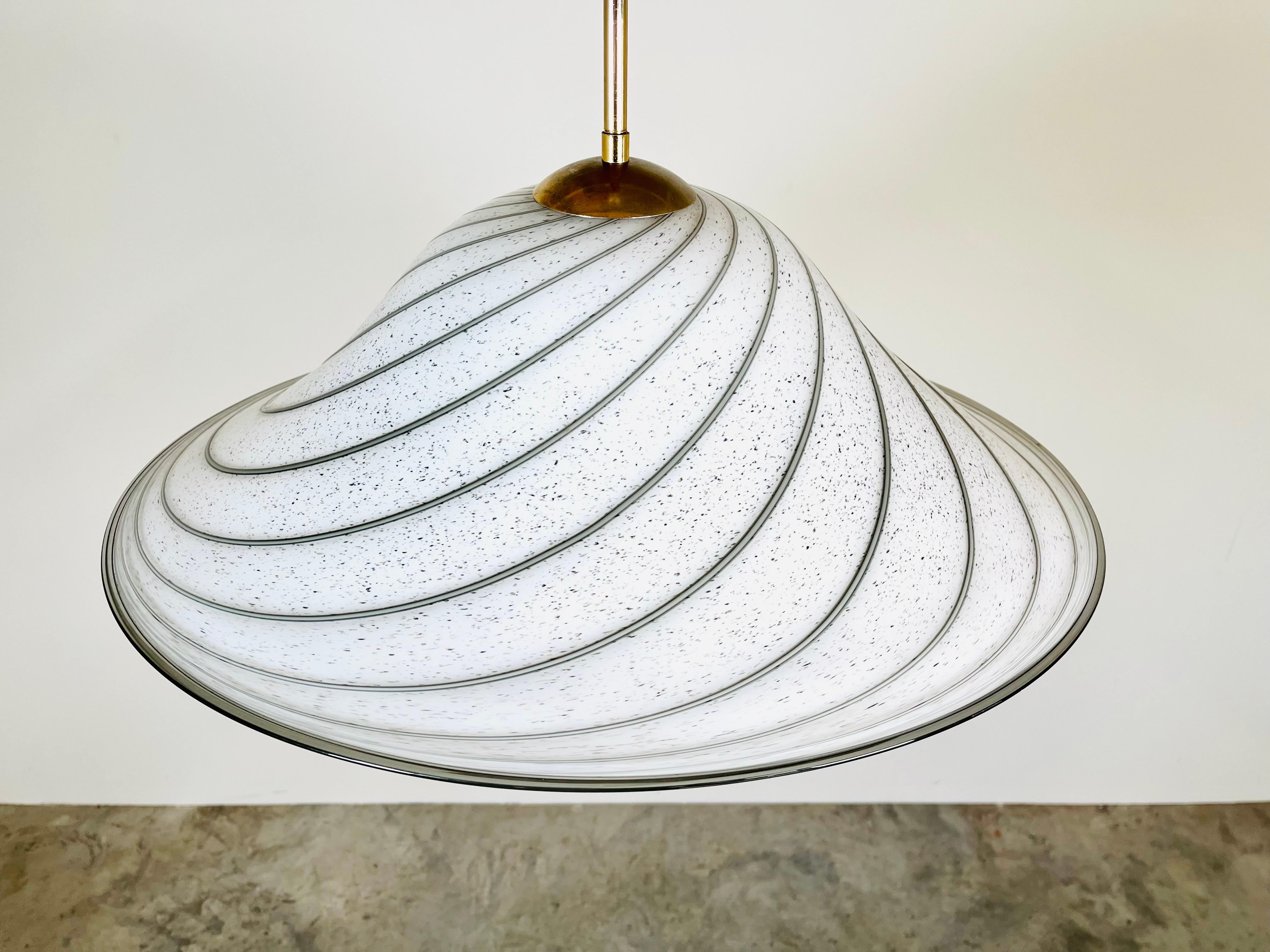 A beautiful hand blown swirl glass hanging pendant light by Murano for effetre international, Italy circa 1970. Soft white in hue having dark accents blown in throughout along with tiny bubbles that offer the shade depth that draws you in. 
