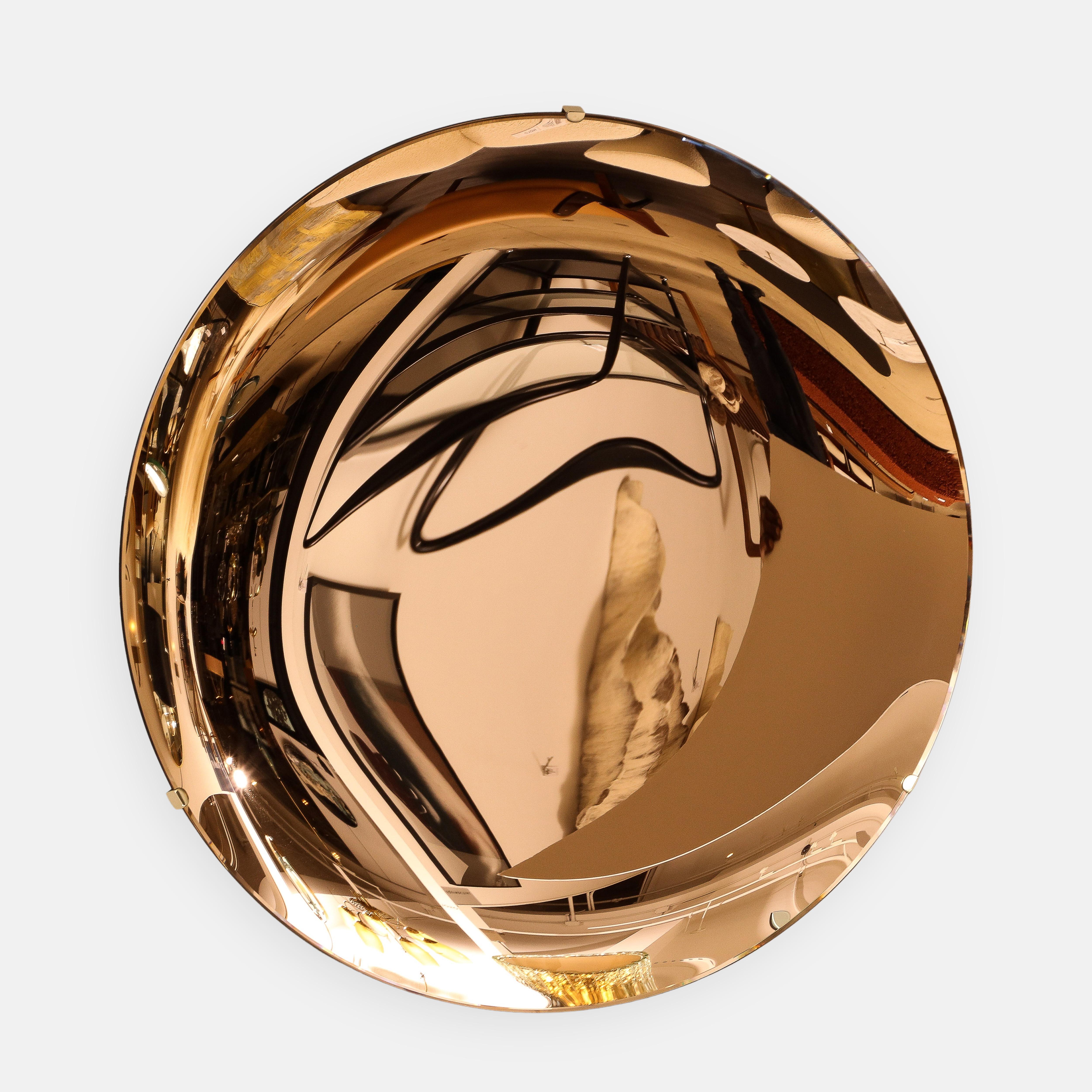 Effetto Vetro contemporary large round concave colored mirrored glass mounted on a polished brass structure on the back with three mounting clips on the front edges, Italy, 2023. This exquisite mirror is a sculptural work of art, grand and