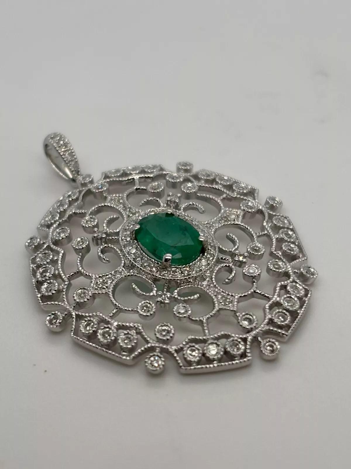 Offered is a stunning EFFY filigree pendant, crafted in solid 14K white gold, featuring a richly colored natural oval-cut emerald surrounded by over one carat of natural diamonds. The vintage-inspired openwork design blends old-world charm with