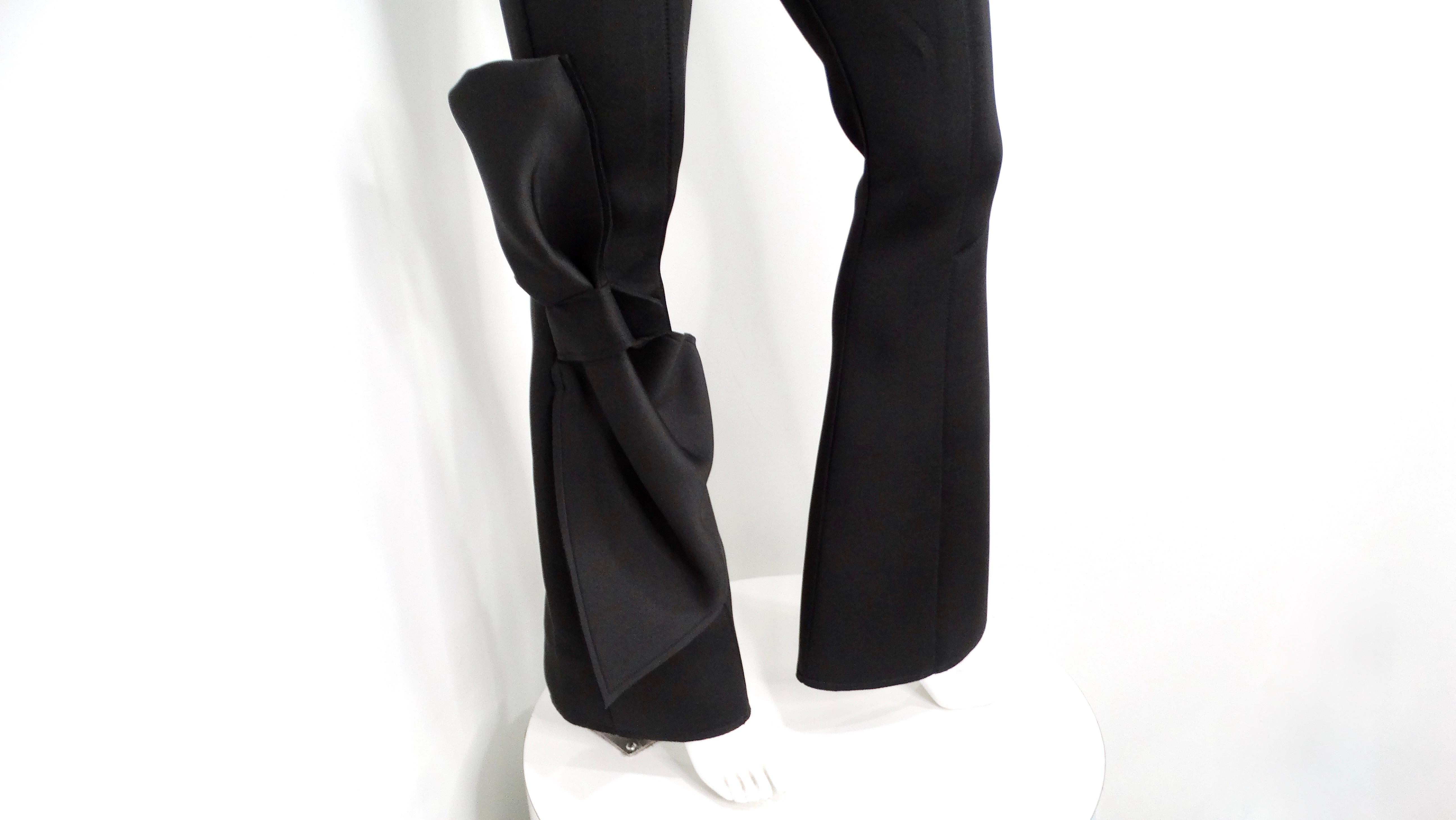 Efrat Kalig Couture Bow Detail Flare Dress Pants are a striking addition to any sophisticated wardrobe. Crafted from a thick, stretchy material that resembles scuba fabric, these pants offer both comfort and style. The right pant leg features a