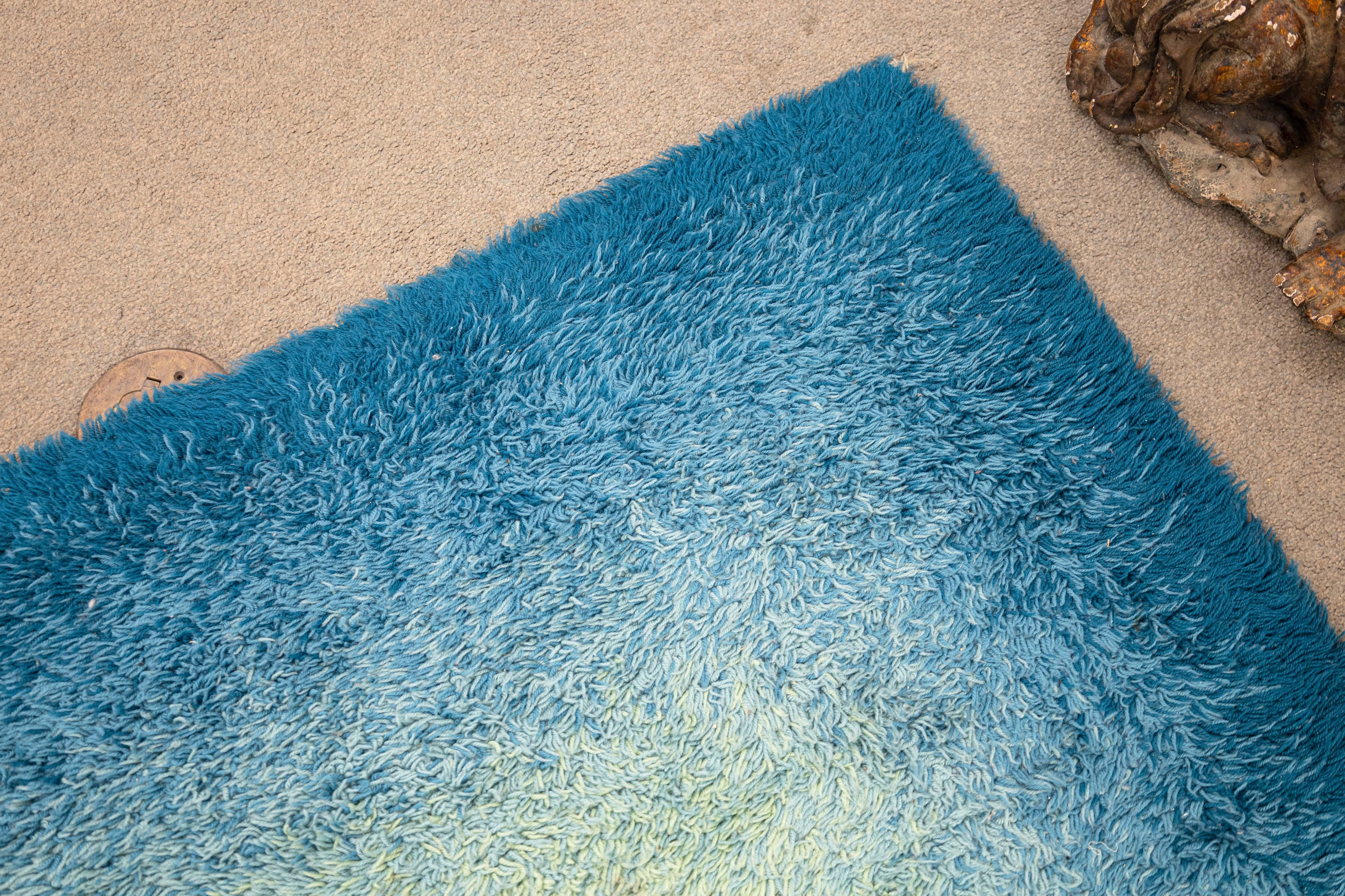 Tapis Ege Rya du milieu du siècle dernier. Ce magnifique tapis danois Rya présente un magnifique dégradé de bleu, avec une base bleue menant à un centre jaune. Ce tapis est fait à la main avec de la laine nouée et comporte encore l'étiquette