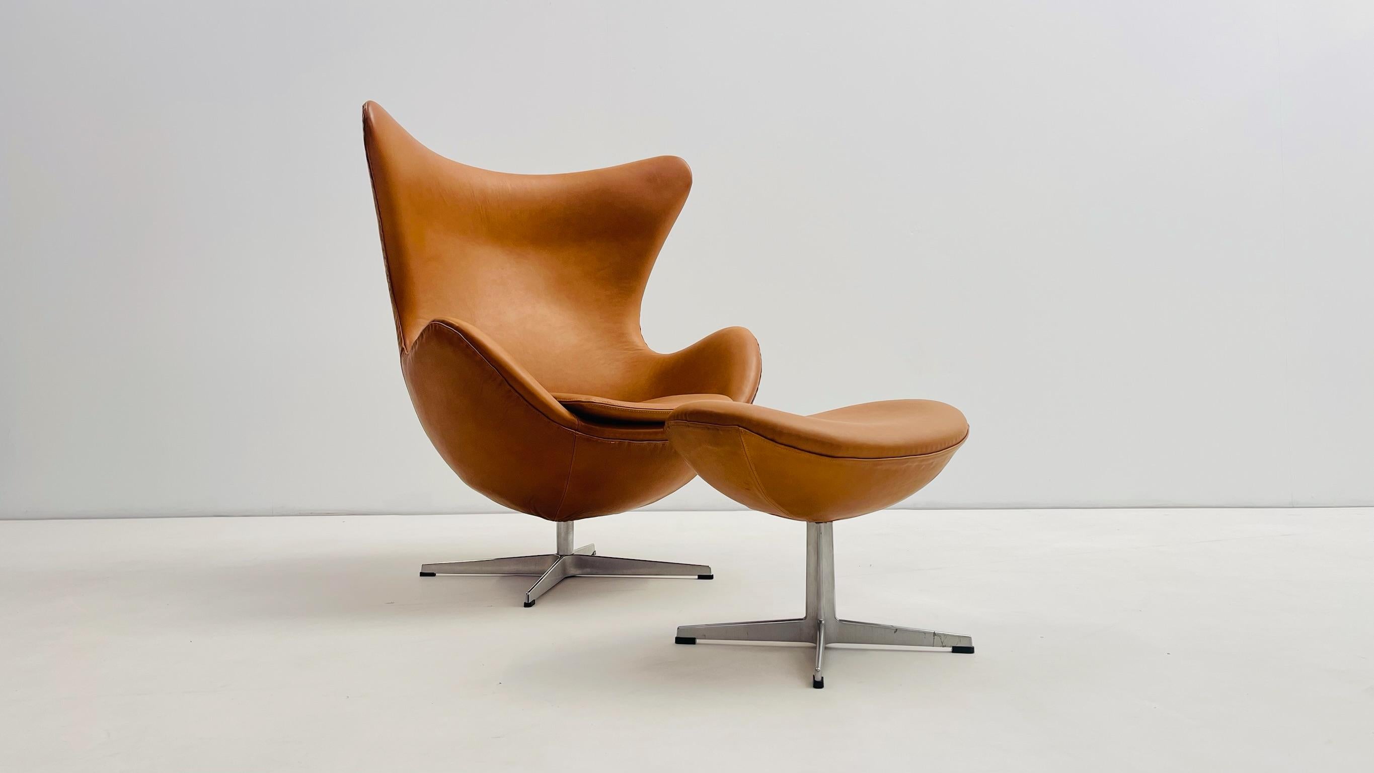 Ein ikonischer Egg Chair von Arne Jacobsen für Fritz Hansen aus den 1960er Jahren, zusammen mit dem Original-Ottoman. Diese klassische Garnitur wurde vollständig mit hochwertigem cognacfarbenem Leder neu gepolstert, was ihre skulpturale Präsenz