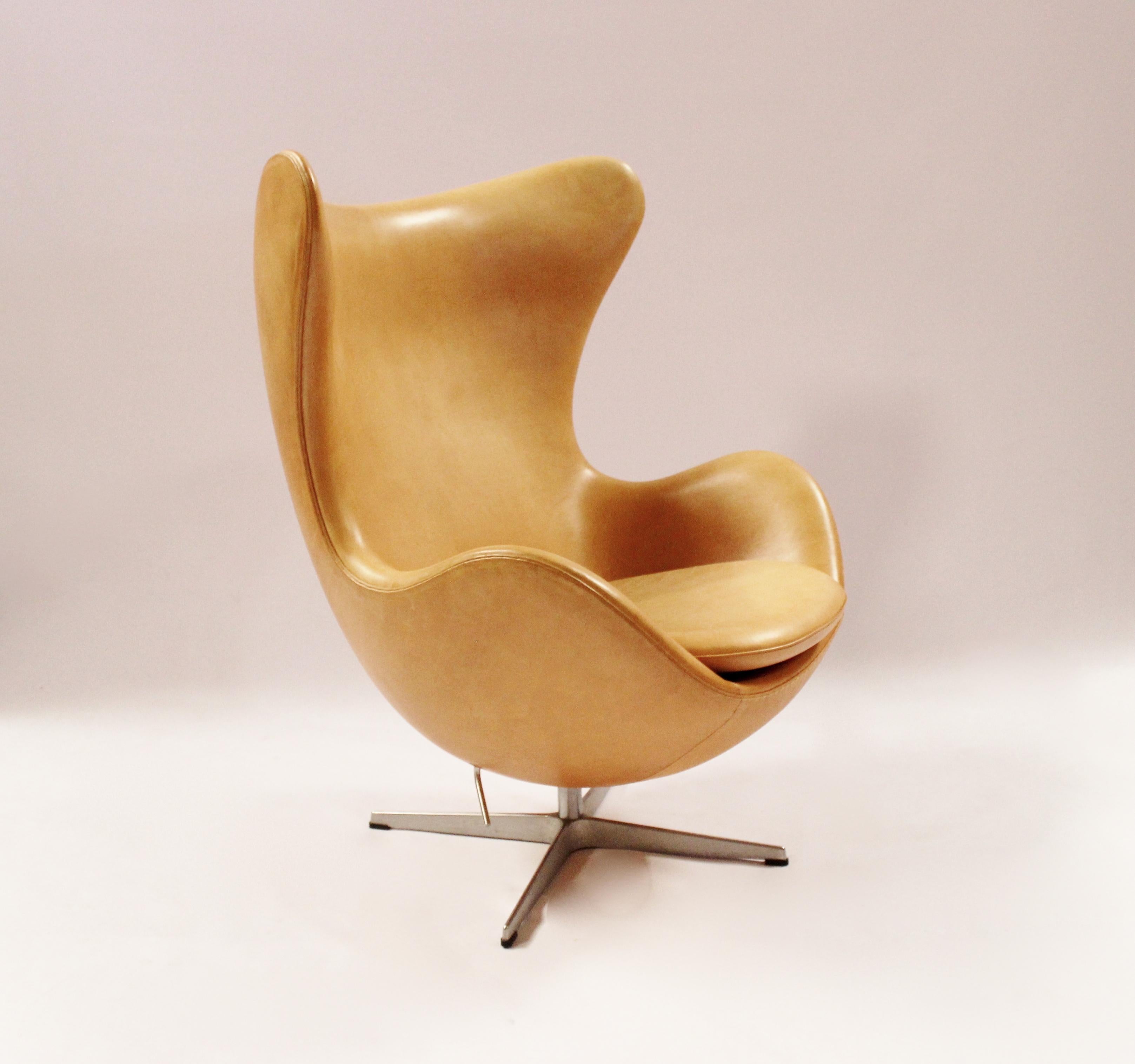 The Egg, model 3316 and stool, model 3127, designed by Arne Jacobsen in 1958 and manufactured by Fritz Hansen in 2003. The chair and stool are originally upholstered with vegetal patinated leather and are in great vintage condition.
