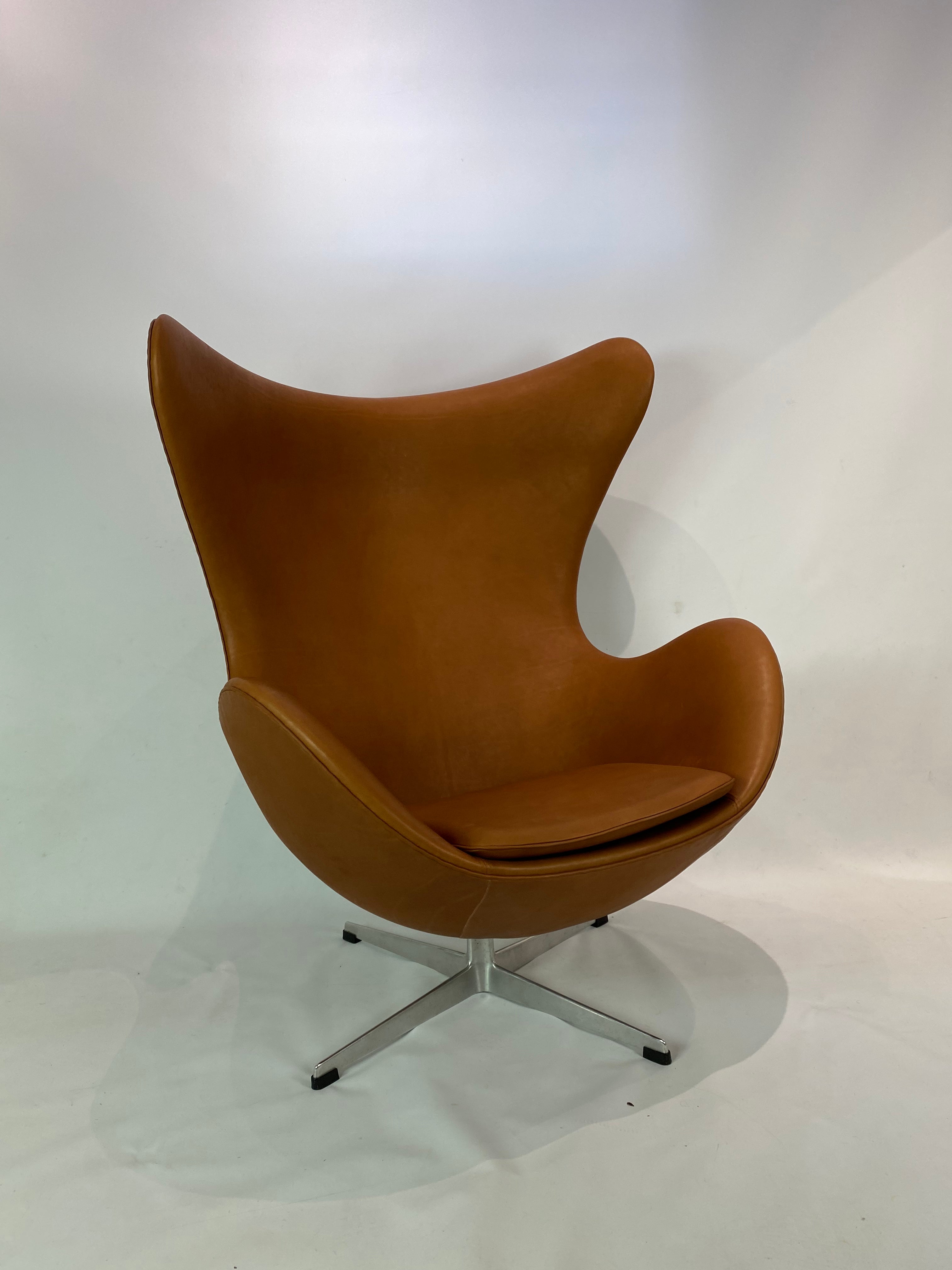 Das Ei, Modell 3316, entworfen von Arne Jacobsen im Jahr 1958 und hergestellt von Fritz Hansen. Der Stuhl ist mit cognacfarbenem, patiniertem Leder gepolstert und befindet sich in hervorragendem Zustand. 

Arne Jacobsen schuf das Ei bereits 1958 im