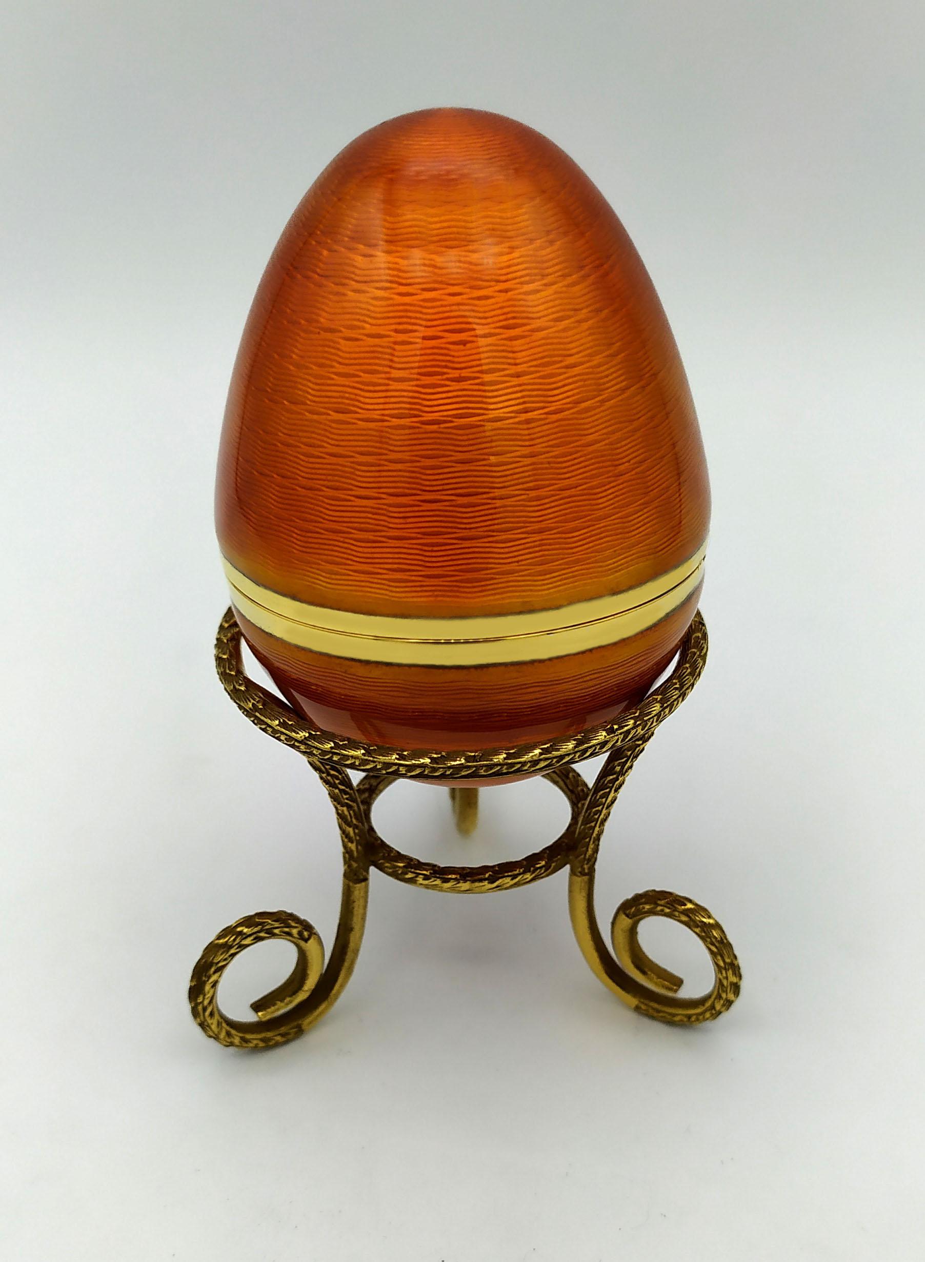 Ei auf Dreibein in 925/1000 Sterlingsilber vergoldet mit durchscheinendem gebranntem Email auf Guillochè, im Stil des russischen Empire, inspiriert von Carl Fabergè Eiern Ende 1800, Anfang 1900. Maße: Durchmesser des Eies cm. 5 cm hoch. 6,8 auf
