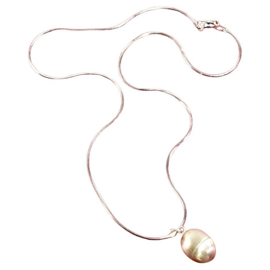 Collier pendentif en forme d'œuf en argent avec un mécanisme à vis et un centre creux pour ranger un talisman. Il est conçu pour que le porteur puisse porter sur lui un objet spécial et personnel qu'il gardera près de son cœur, un peu comme un
