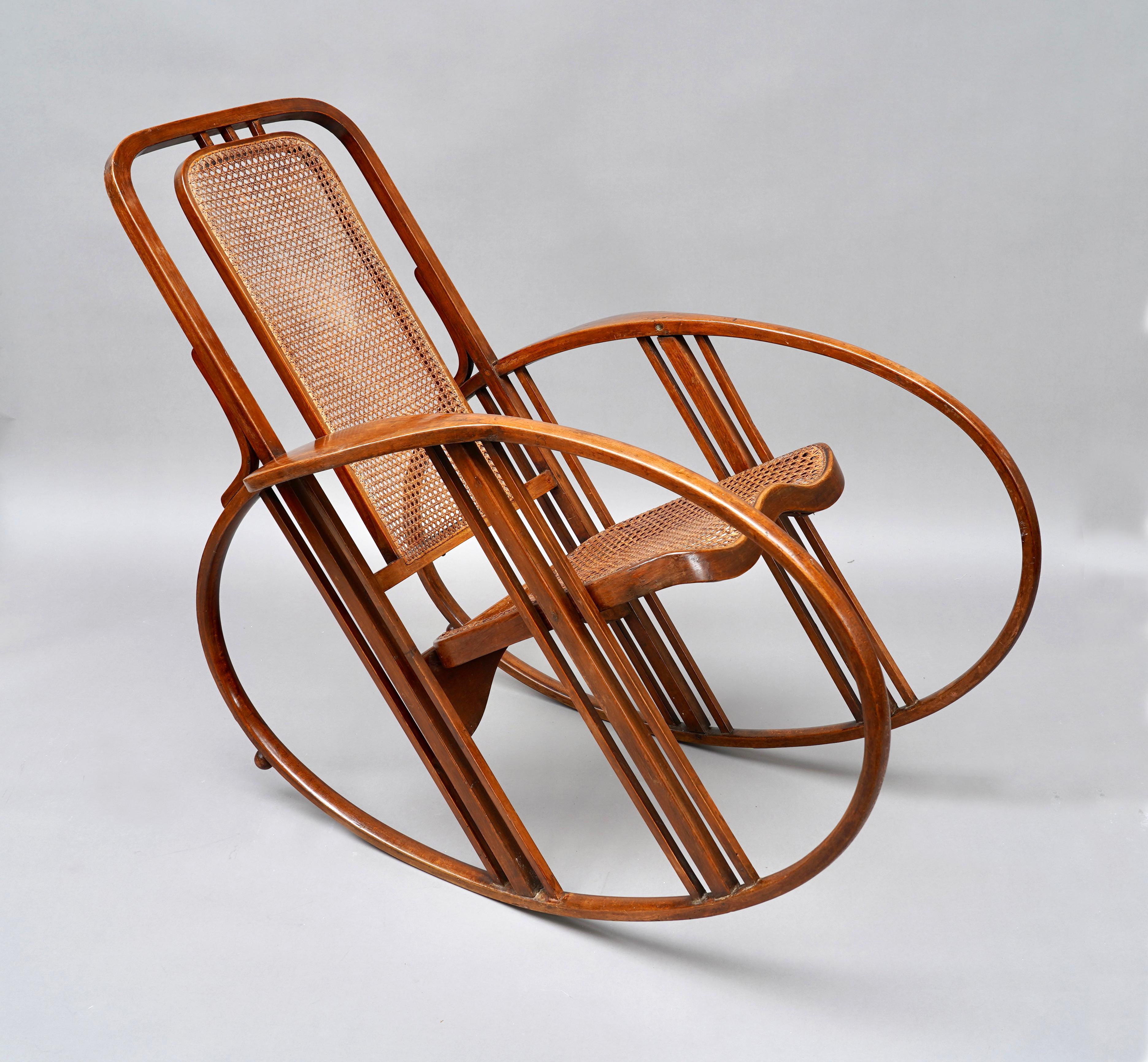 Rare “Egg” rocking chair in curved and stained wood, with caned seat and back. The wide oval-shaped armrests, giving their name to the model, and allowing gentle swinging, are stabilized by small balls at the back. Here we find aerodynamic