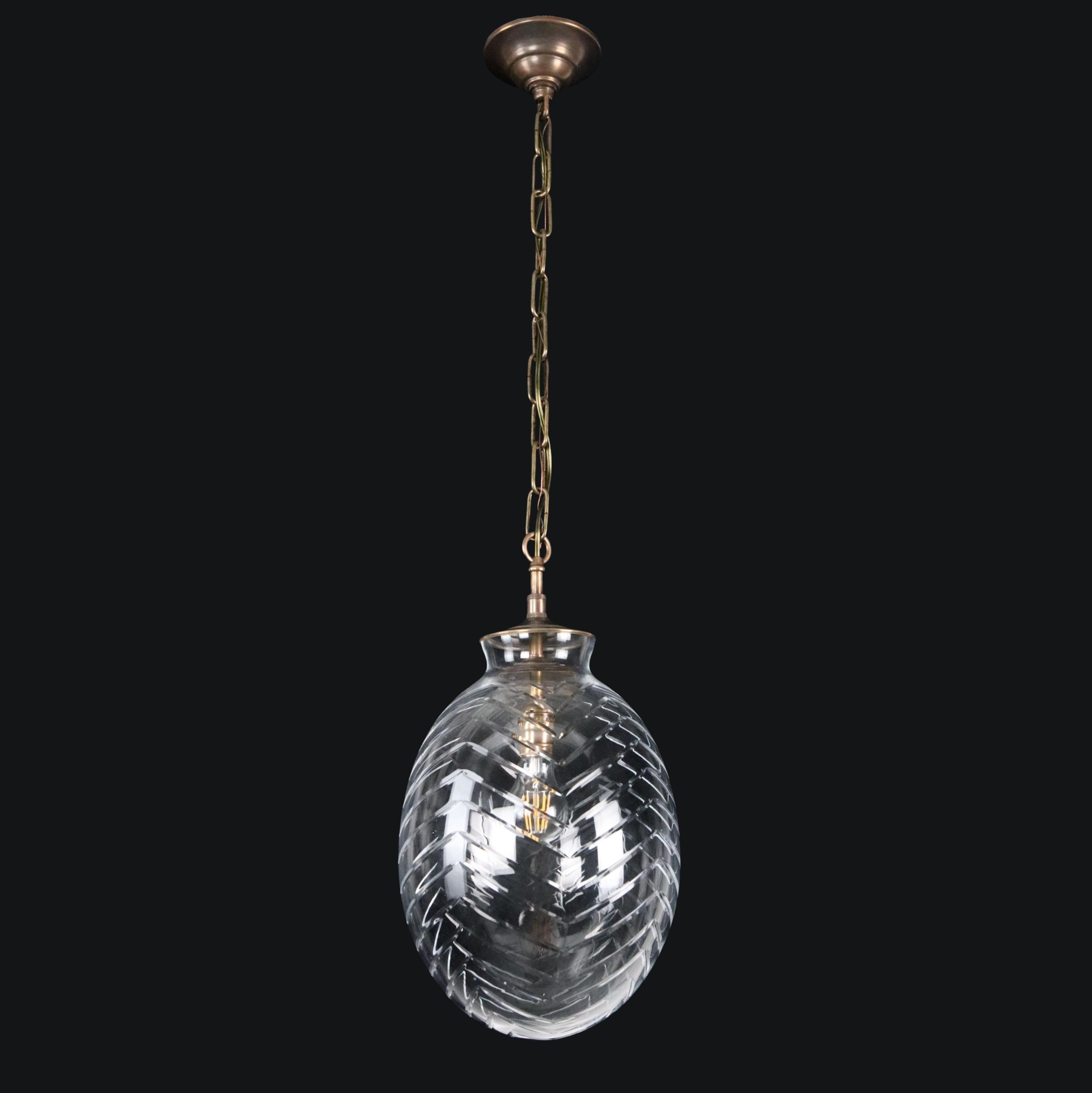 Lámpara colgante de estilo moderno, con un globo de cristal transparente grabado en forma de huevo, combinado con una cadena de latón antiguo de nueva fabricación. Requiere una bombilla estándar Edison de casquillo mediano. Limpiado y restaurado.