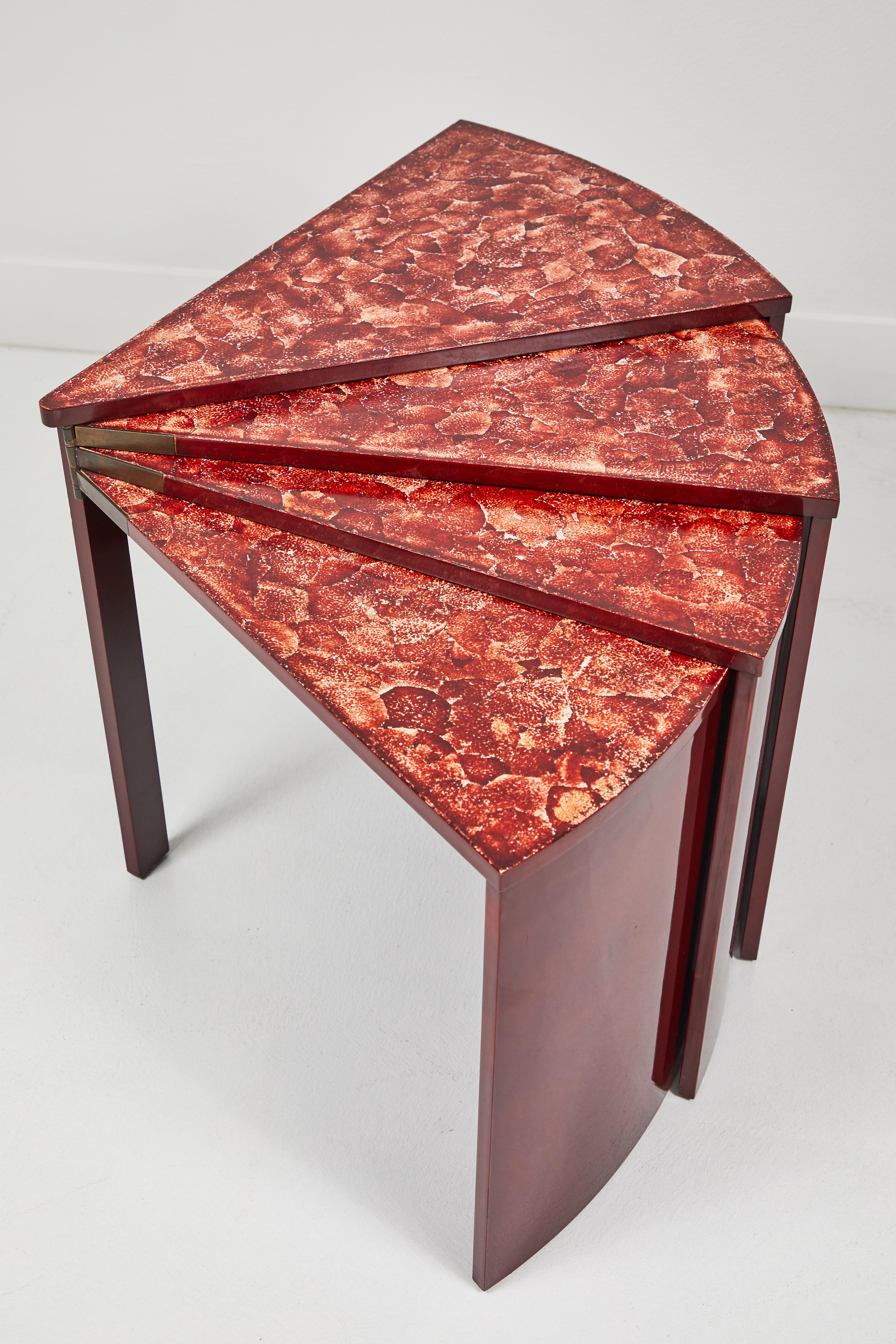 This set of tables modeled after the original Jean Dunand feature an Oxblood red lacquer with inset egg shell decoration on the tops. The tables are hinged at one end and can be stacked inside one another or left extended and cascading. When fully