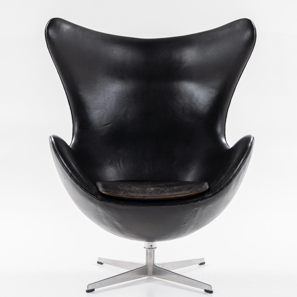AJ 3316 - 'The Egg' lounge chair in original black leather, tilt function and on an old aluminium base with matching footstool. Arne Jacobsen / Fritz Hansen