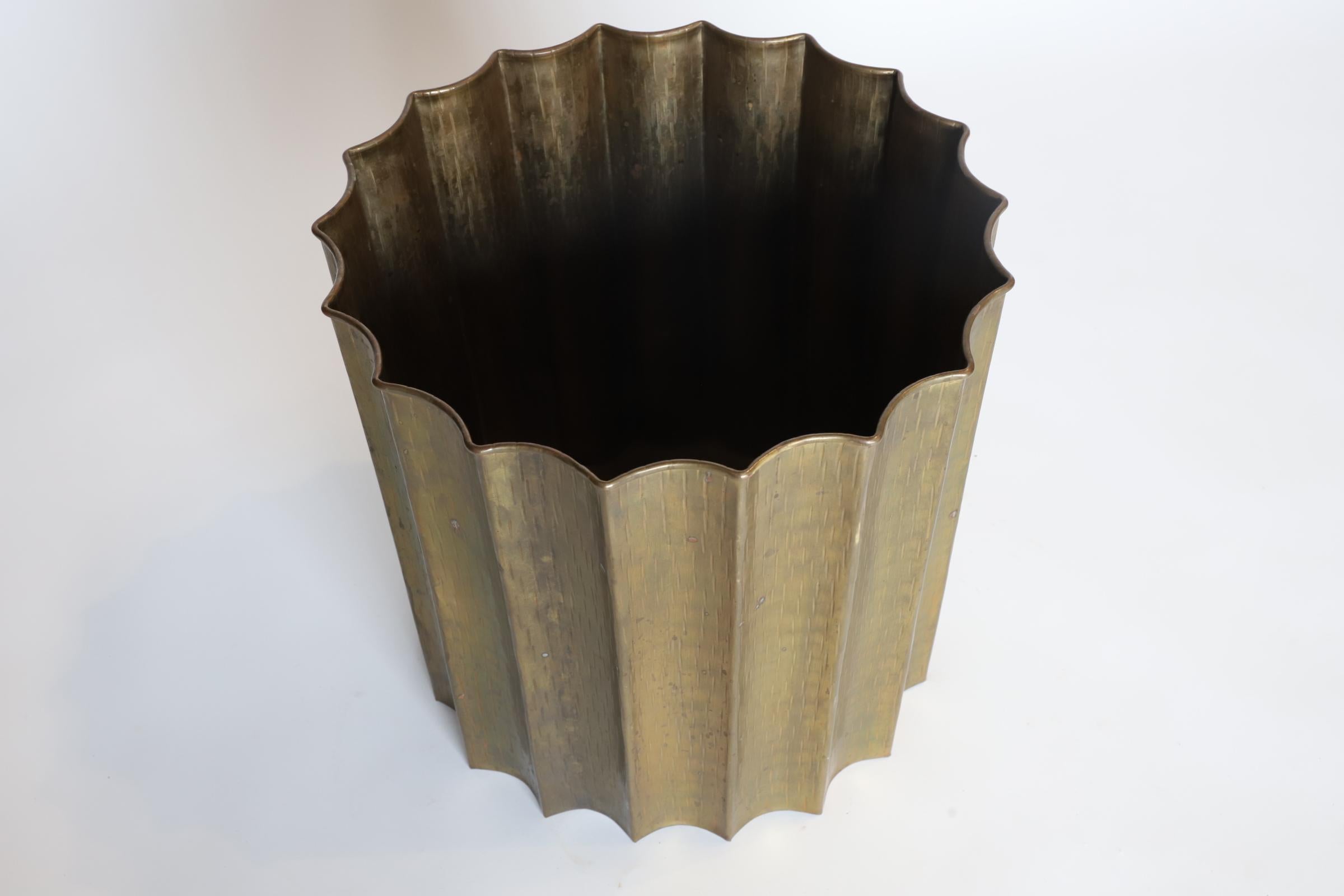Una fioriera smerlata in ottone martellato a mano è un contenitore decorativo tipicamente utilizzato per esporre piante o fiori. È realizzato in ottone, un metallo resistente e attraente noto per la sua calda tonalità dorata. La superficie della