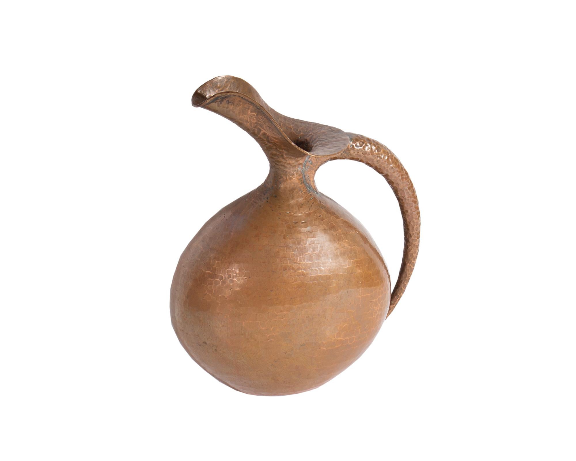 A hammered copper pitcher or ewer designed by the Italian designer Egidio Casagrande (1911-1962). This pitcher has a round body and tapered handle on one side. The underside of the pitcher is marked 