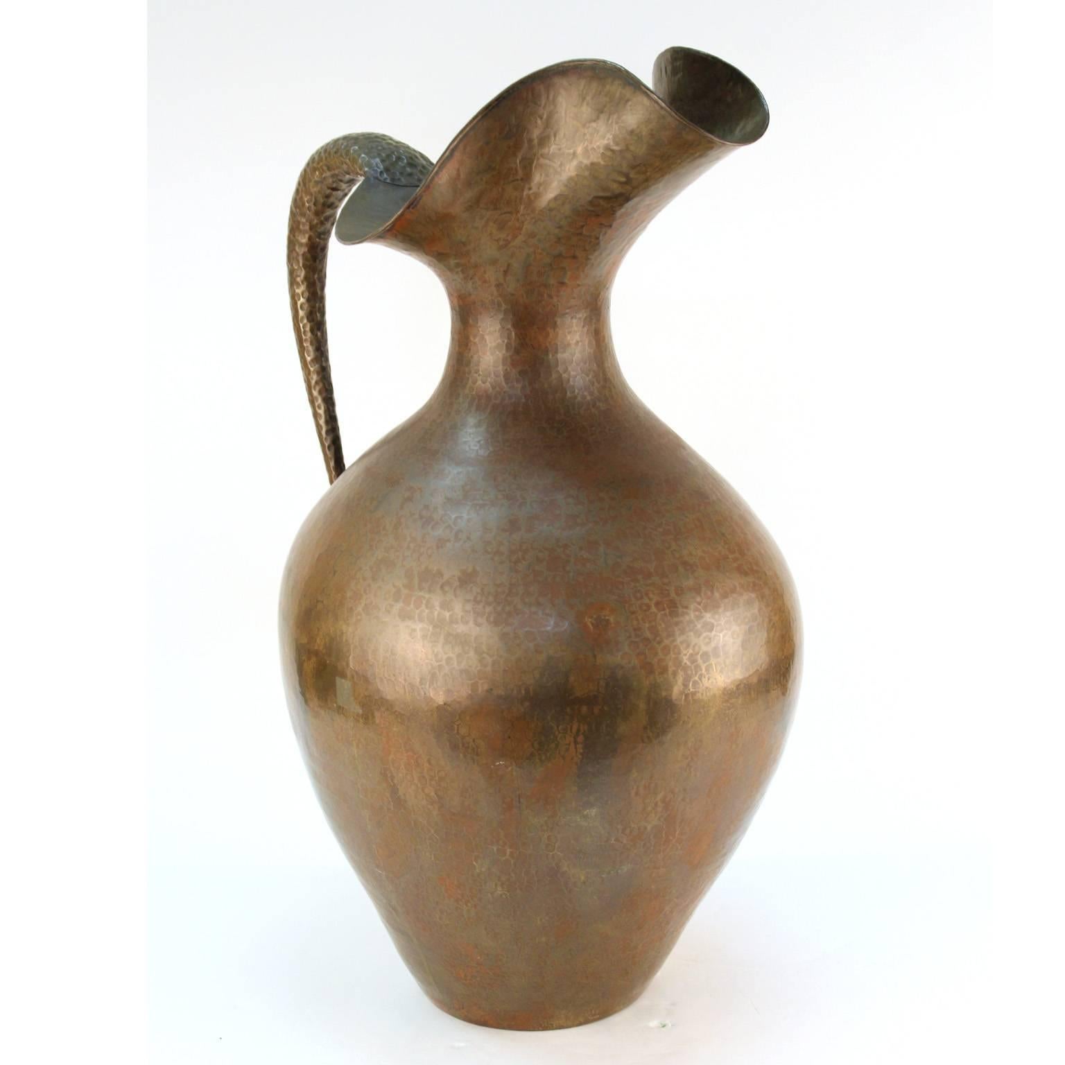 A monumental modernist style brass repousse pitcher made in the 1930s-1940s by Italian designer Egidio Casagrande (1911-1962). Casagrande is renown for his work as a master craftsman who worked on the metal designs and armors for classic Hollywood