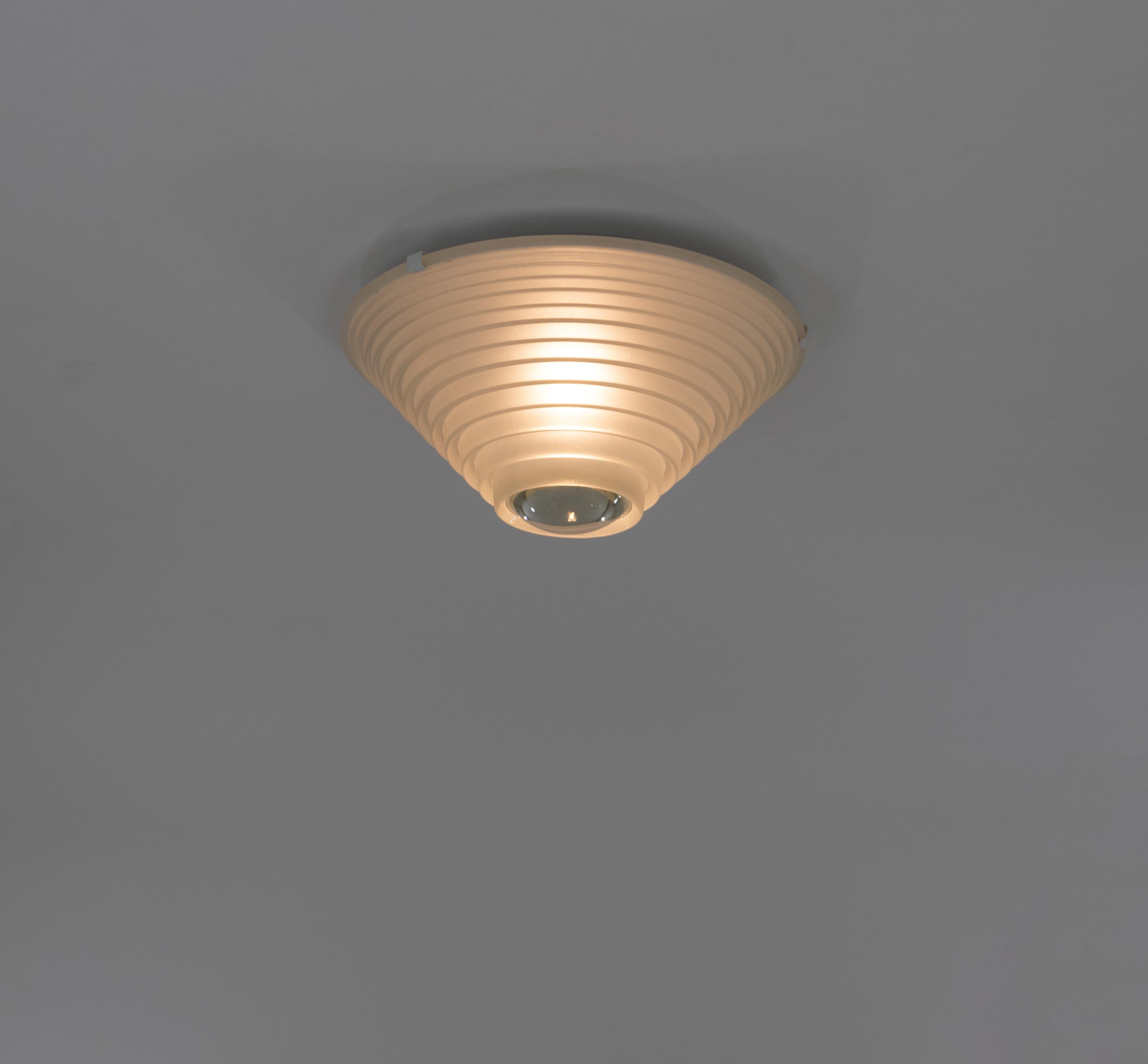 Egina 38 Decken- oder Wandleuchte mit diffusem und konzentriertem Licht, entworfen von Angelo Mangiarotti für Artemide im Jahr 1979.

Sie besteht aus einem sandgestrahlten Glasschirm mit einer großen Linse in der Mitte und einem weiß lackierten