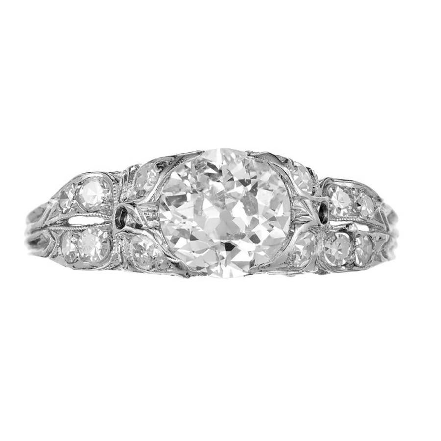 Step into an era of opulence with our 1.17ct Old European cut Diamond, 1900's Edwardian platinum engagement ring, a true masterpiece that harks back to the elegance of a bygone age. The diamond glistens with an enchanting brilliance, its facets