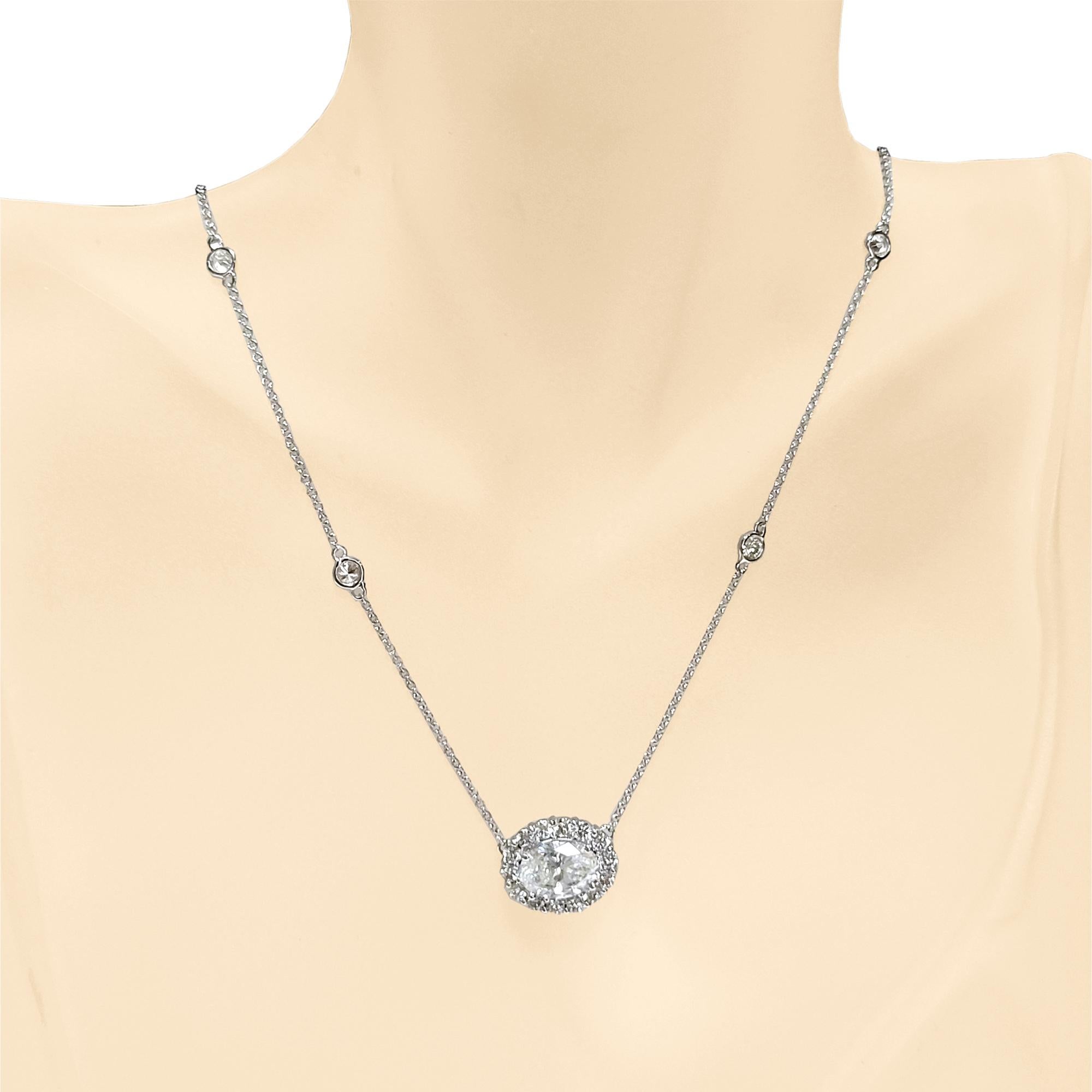 An F/SI3 EGL Certified 2.15 Ct Oval diamond sits in the center of a Beautiful  handcrafted Pendant with halo set with 14 Perfectly matched Round Brilliant Diamonds. It sits on a  diamond by the yard necklace with 4 bezel set Round brilliant