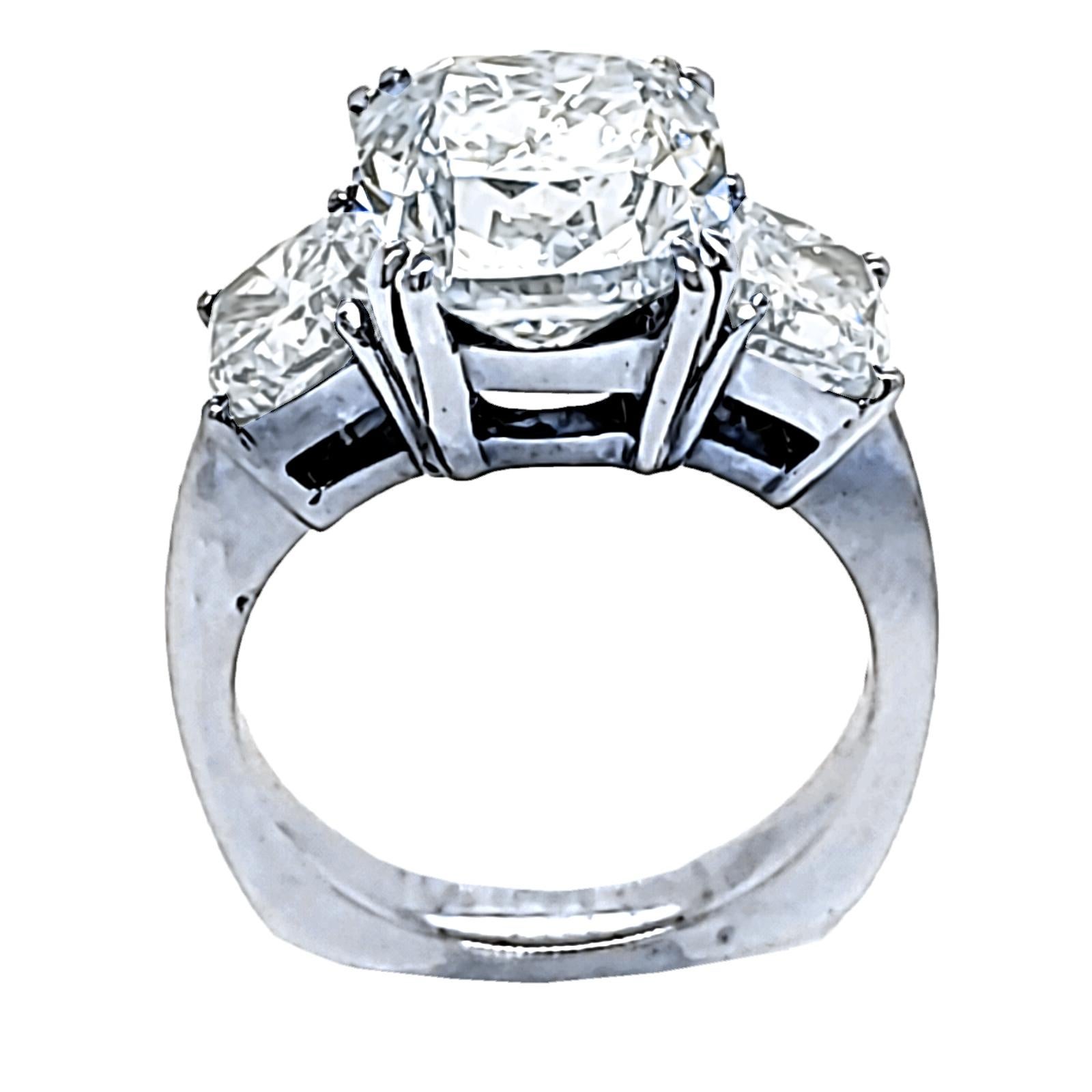 A beautiful square Cushion K/VS2 EGL certified center Diamond set in a traditional square shank 18k gold 3 stone ring with 2 1 carater cushions on the side. Total diamond weight of 2.01 Ct. on the side. 

Center stone: 5.05 Ct EGL Certified K/VS2