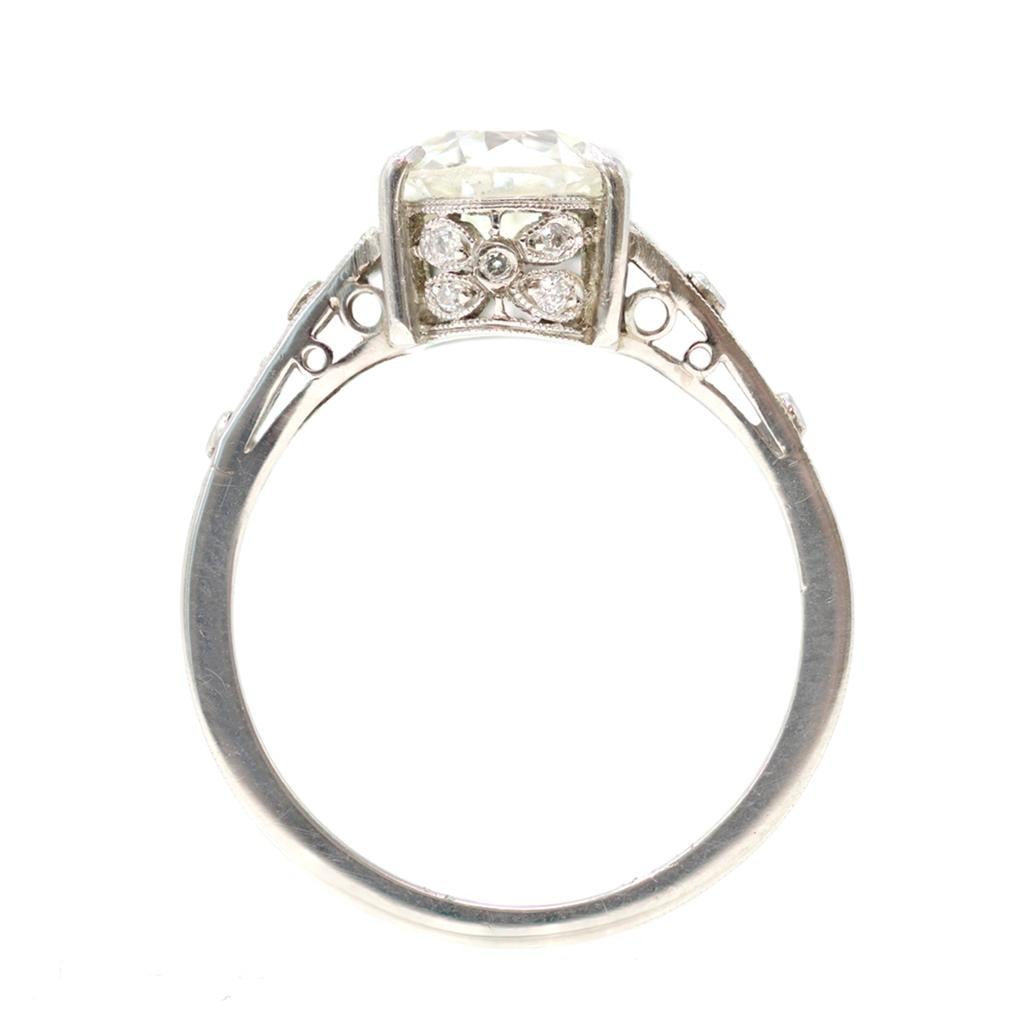 A vintage lace engagement ring featuring a solitaire diamond accompanied by an EGL Report stating the Old European-cut diamond is I color and SI1 clarity. The mounting is accented with an estimated weight of 0.15 carats of old mine-cut diamonds. The