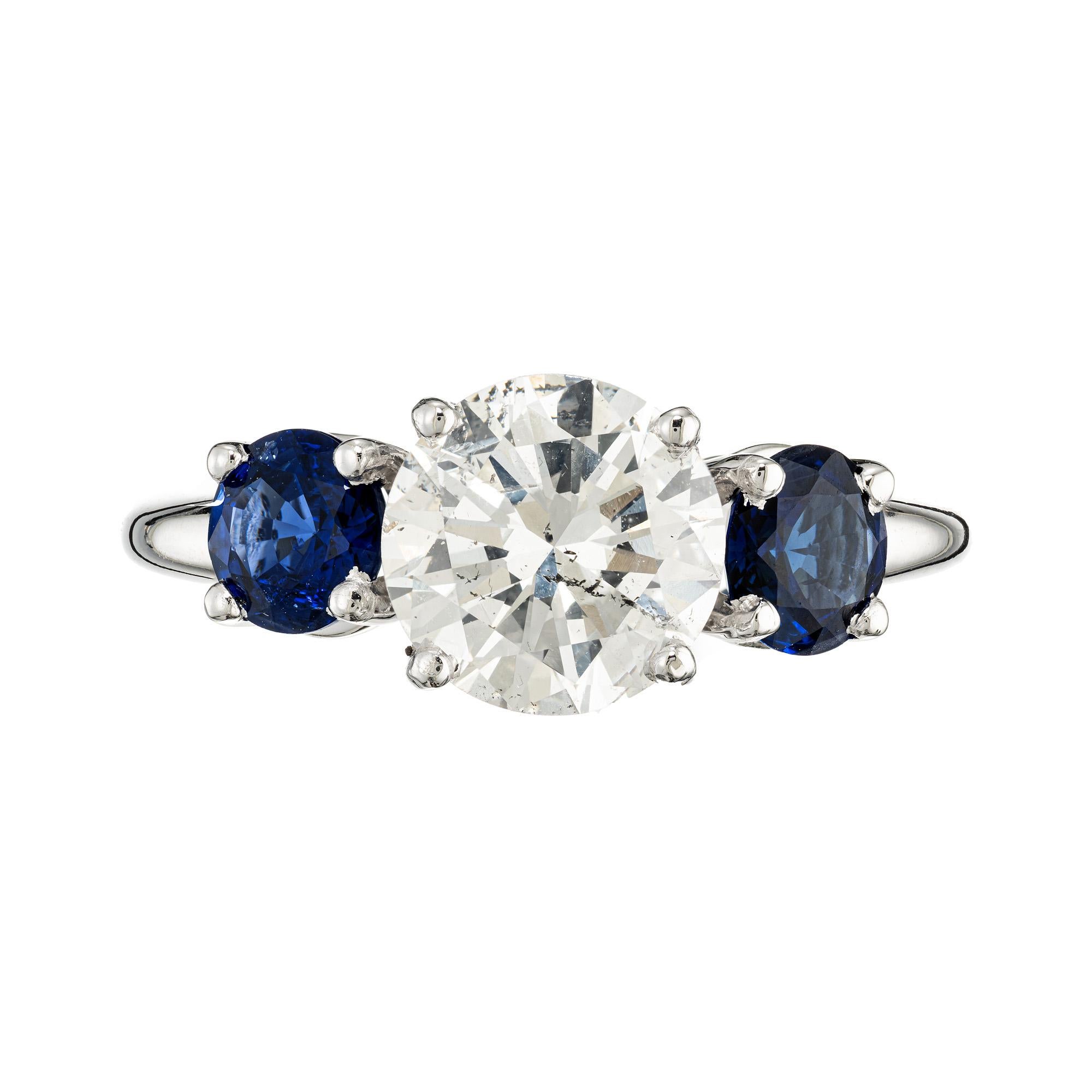 Diamond and Sapphire platinum classic three stone engagement ring. The dazzling 1.93-carat diamond takes center stage, flanked by two vibrant round sapphires and in lustrous platinum, the ring exudes luxury and durability. The diamond is certified