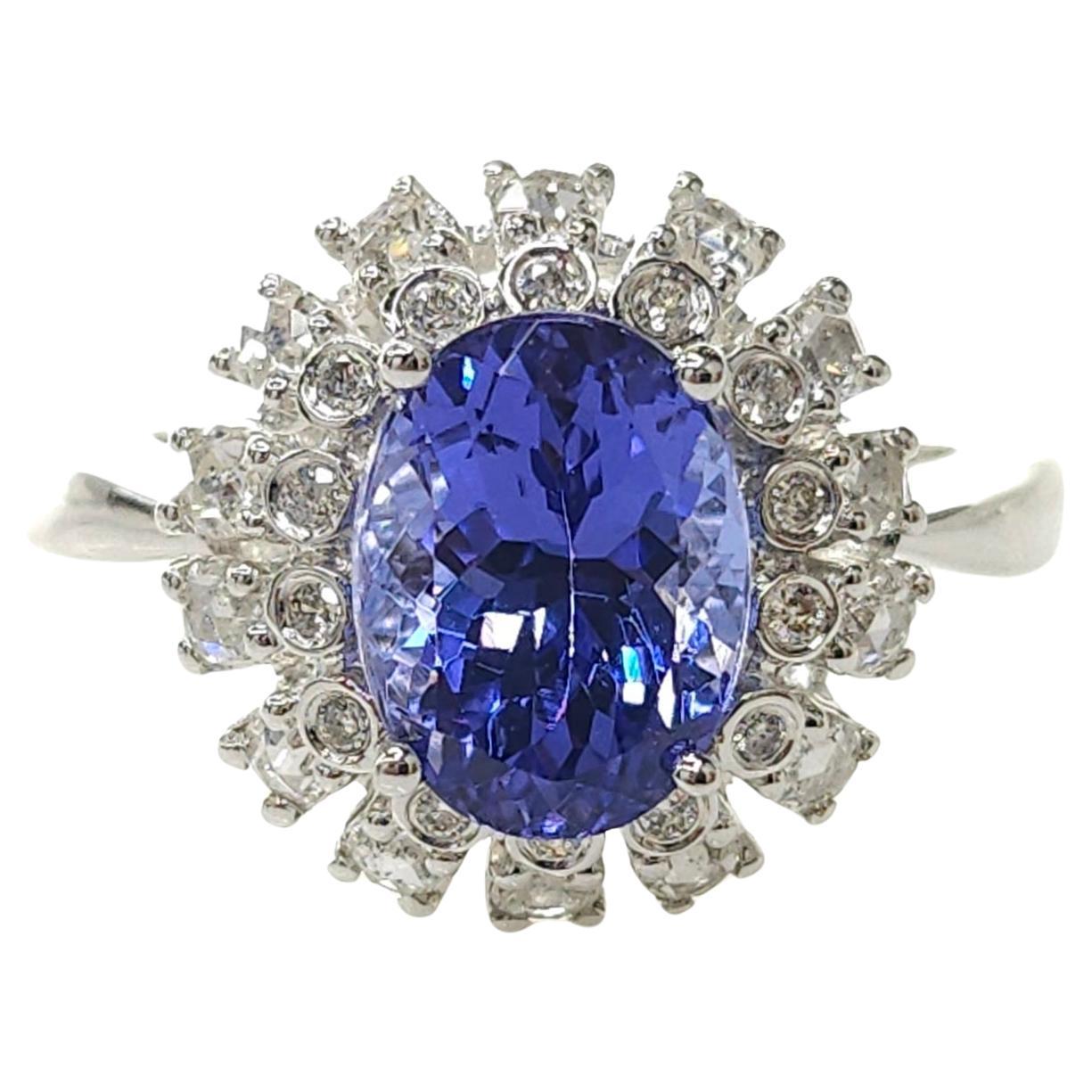 Indulge in the enchanting allure of this breathtaking cluster-style ring featuring a mesmerizing IGI Certified 2.76 Carat tanzanite in a vivid bluish-violet color, expertly crafted in an oval shape that exudes elegance and sophistication. This