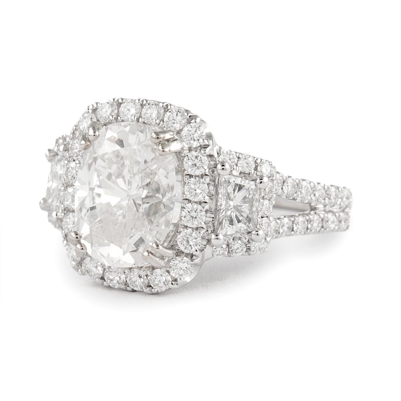 Superbe bague de fiançailles à trois pierres avec halo, certifiée EGL.
Poids total des diamants : 4,68 carats.
Diamant taille coussin de 3,51 carats, certifié EGL. Couleur I et pureté SI3. Complété par 2 trapèzes et 62 diamants ronds de taille