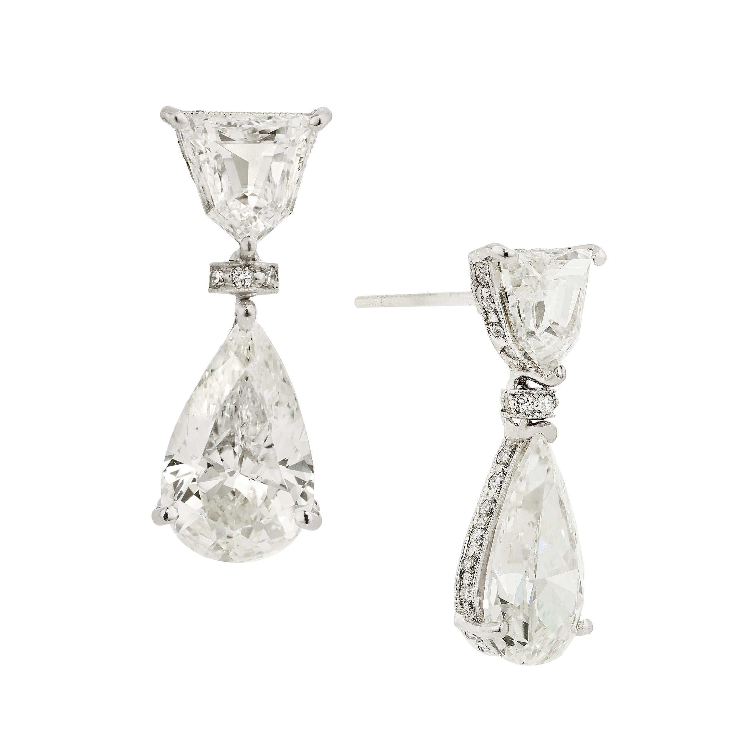 Simply stunning platinum and diamond earrings featuring a Shield-shaped Diamond set with 3 prongs with Pear-shaped Diamonds set with 3 prongs dangling beneath.  There are an additional 64 bead set round brilliant cut diamonds that are set into the