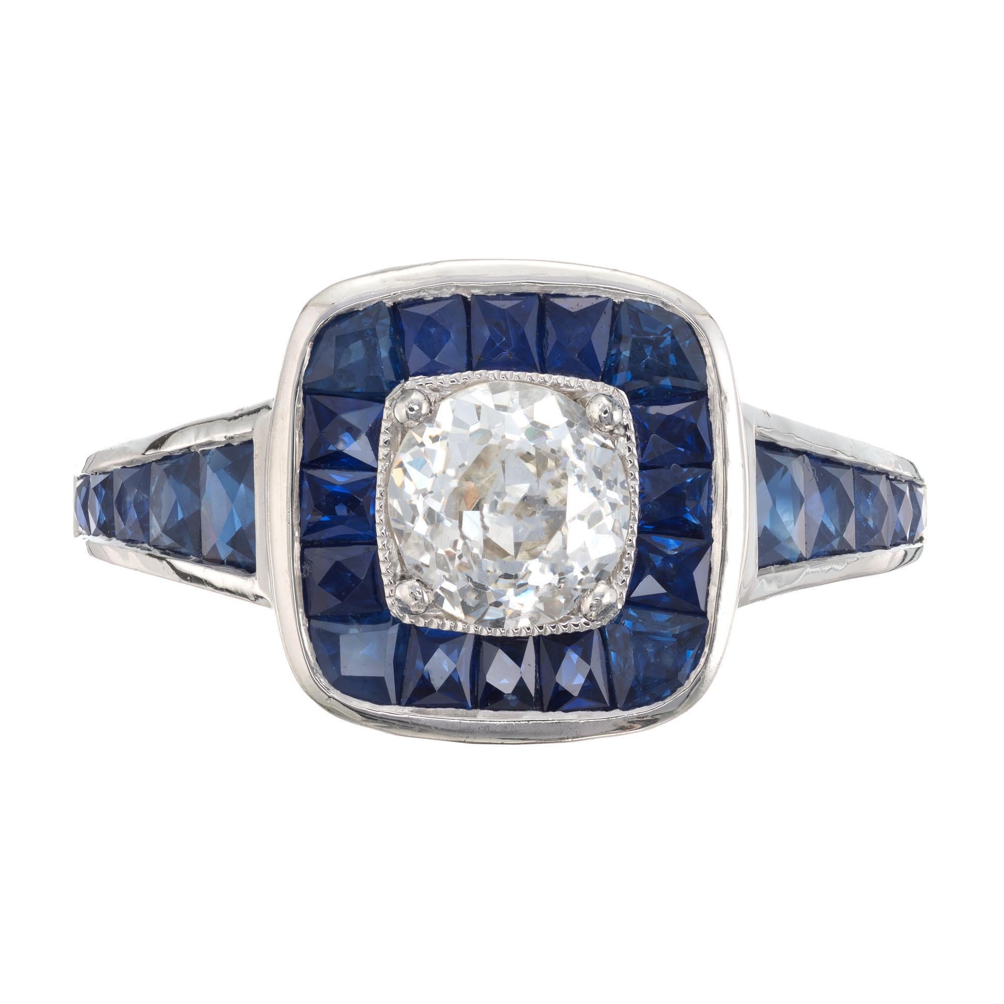 Diamond and sapphire engagement ring. Old European center stone with a halo of calibre cut sapphires in a platinum setting with calibre cut sapphires along both sides of the shank.  Created in the Peter Suchy Workshop. 

1 old European cut diamond,