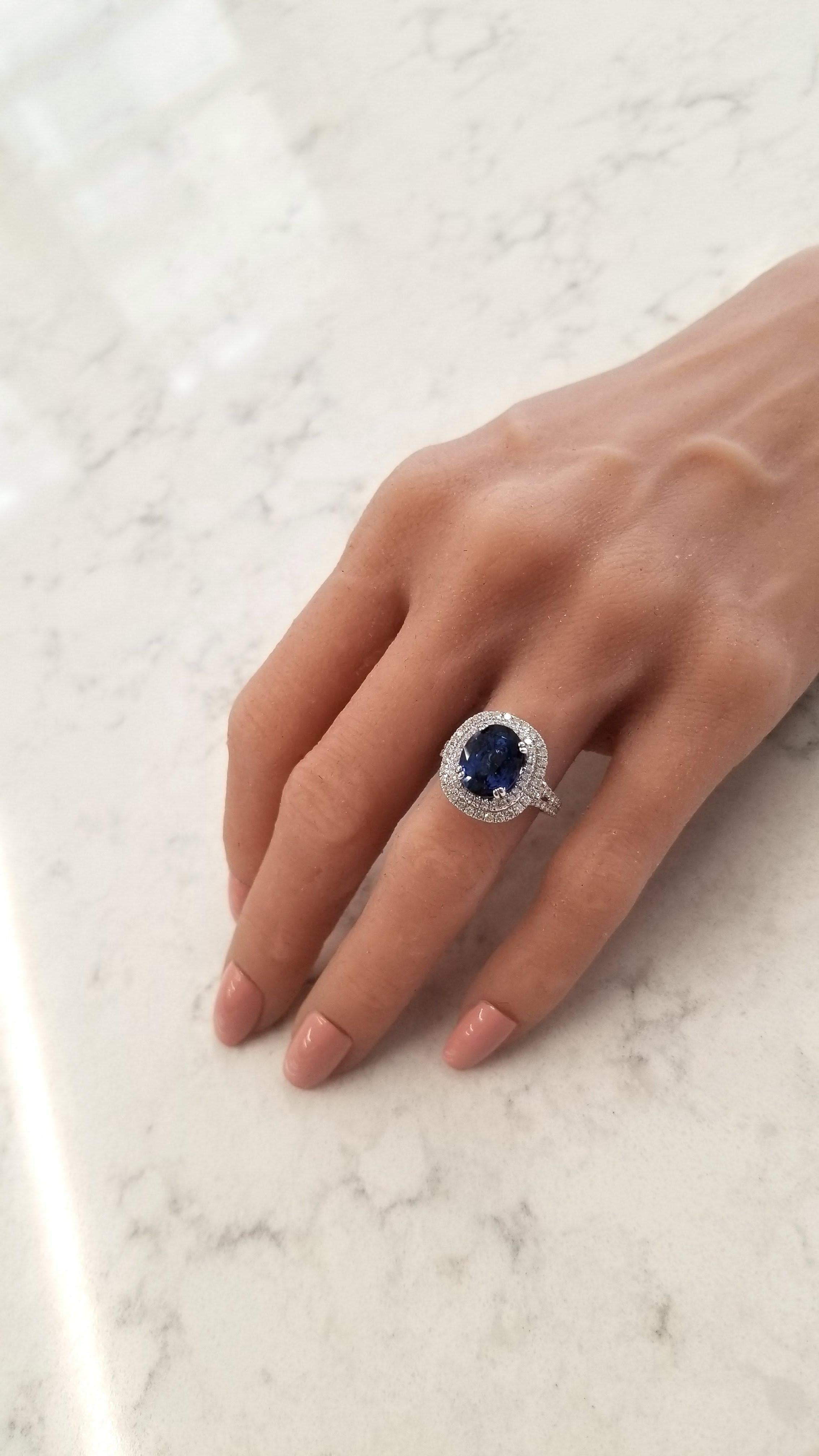 This is a 6.17 carat oval blue sapphire and measures 10.77x8.75mm. The gem source is Sri Lanka; its color is royal blue; its transparency and luster is excellent. Scintillating round brilliant cut diamonds adorn this ring in a sparkling halo around