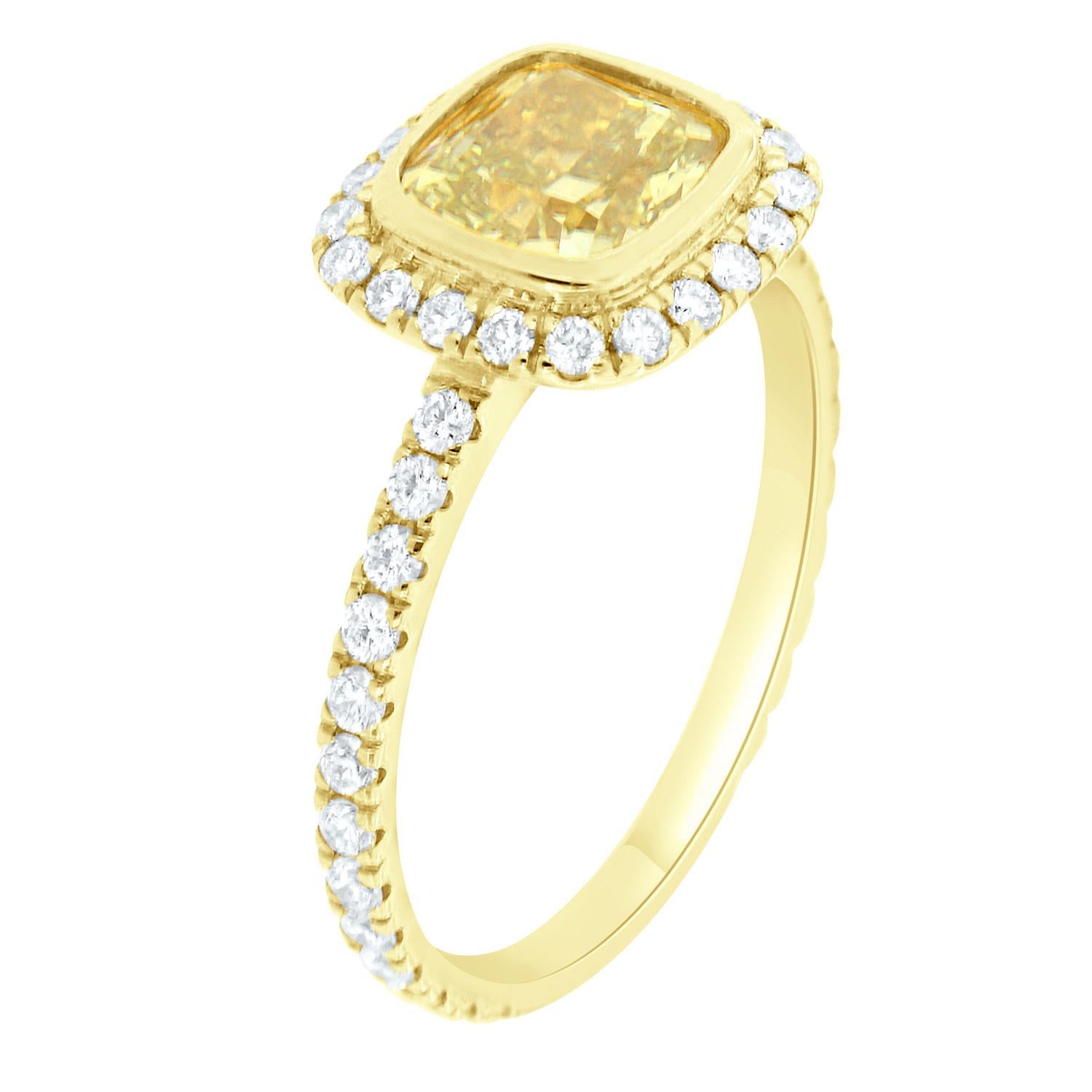 This 18K Yellow gold ring features a 1.52 - Carat Elongated Cushion Natural Yellow Diamond bezel set encircled by a halo of brilliant round diamonds on a one-row 1.7 mm wide band. The diamonds are Micro-Prong set on 75% of the band. The diamond's