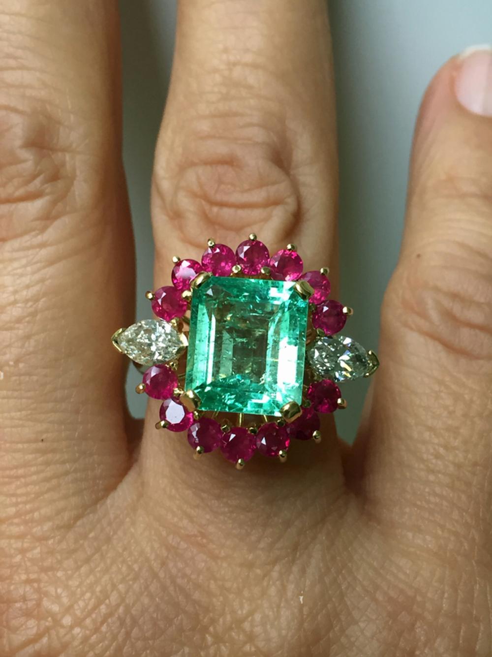 This beautiful 18K yellow gold ring center a beautiful Colombian emerald and is dramatic adorned with rubies and diamonds. 
Primary Stone: Natural Colombian Emerald (Minor Oiled)
Shape Or Cut: Emerald Cut
Emerald Weight: 5.00 Carats (1