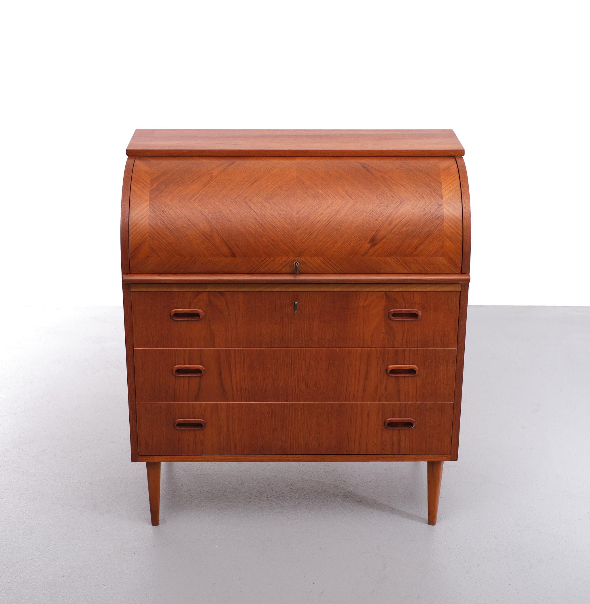 Highly decorative yet functional Scandinavian Mid Century Modern chest of drawers with roll top. The roll top has a geometrical veneer pattern. Under the roll top is a sliding desk shelf, Two small drawers and Three boxes. This cabinet stands on