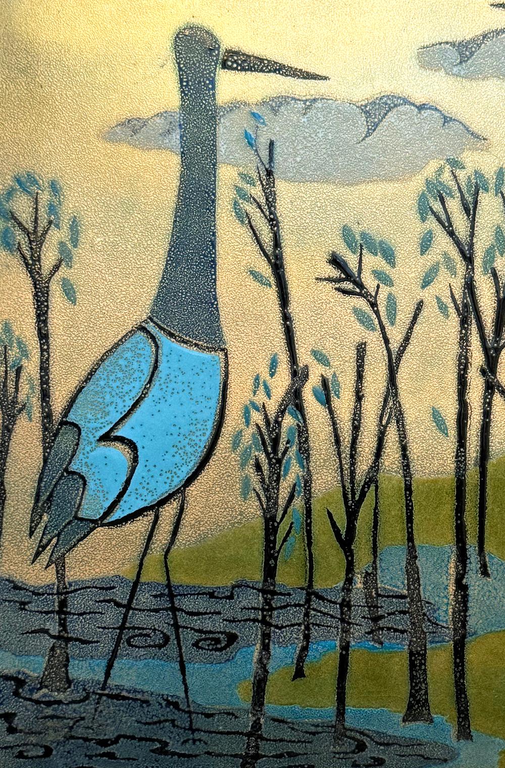 Magnifiquement exprimé dans des tons de bleu, de gris, de vert et d'or, ce fabuleux panneau d'émail du milieu du siècle montre une aigrette au bord d'un ruisseau, avec des jeunes arbres en noir et en ardoise s'étendant vers la droite.  L'émail