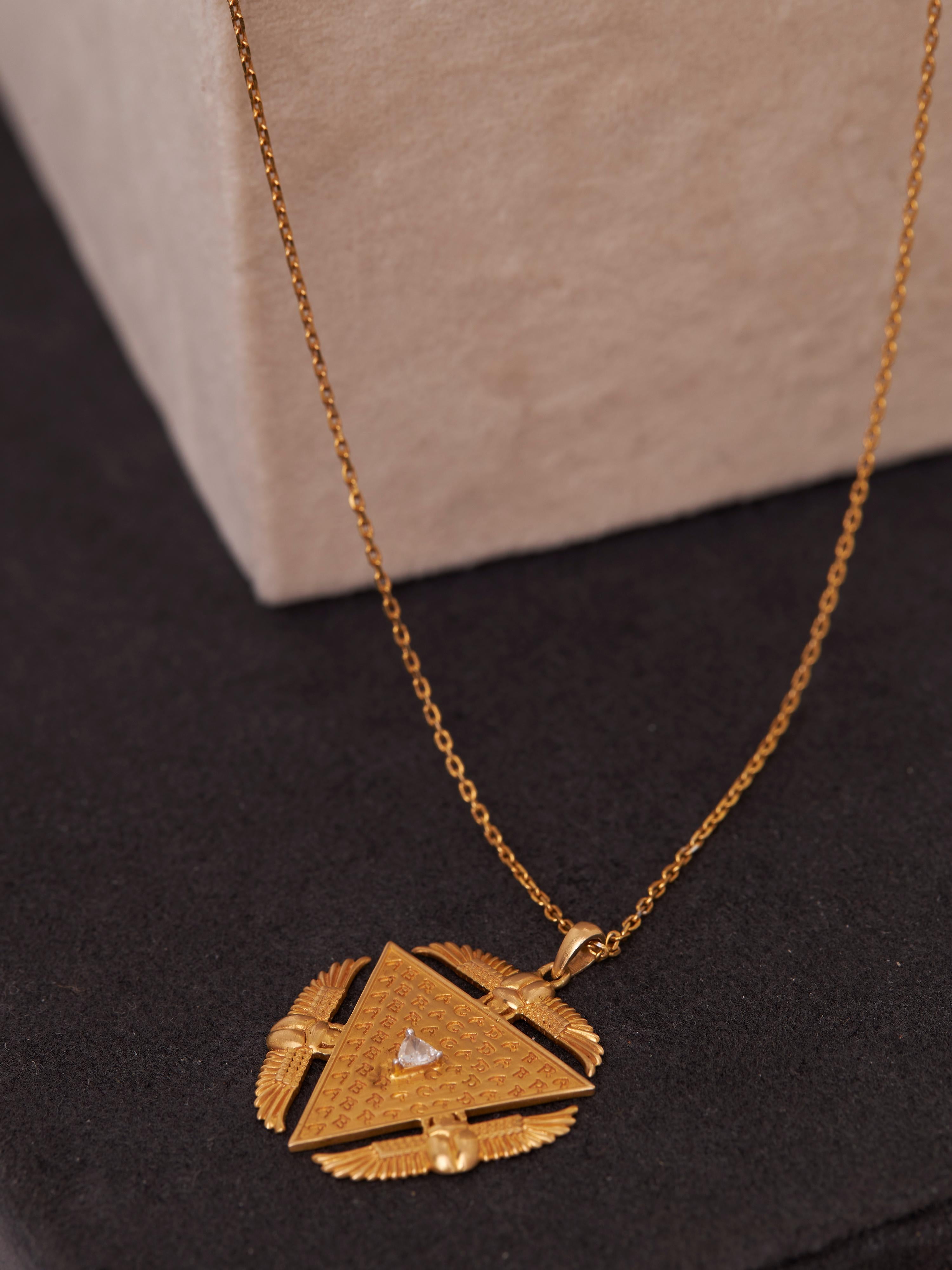 Introducing the Abracadabra Scarab Talisman, a powerful symbol of creation and renewal, rooted in the rich heritages of European and Egyptian traditions. Crafted in 18KT gold (5.924 gm) and adorned with a sparkling natural triangle diamond (0.13