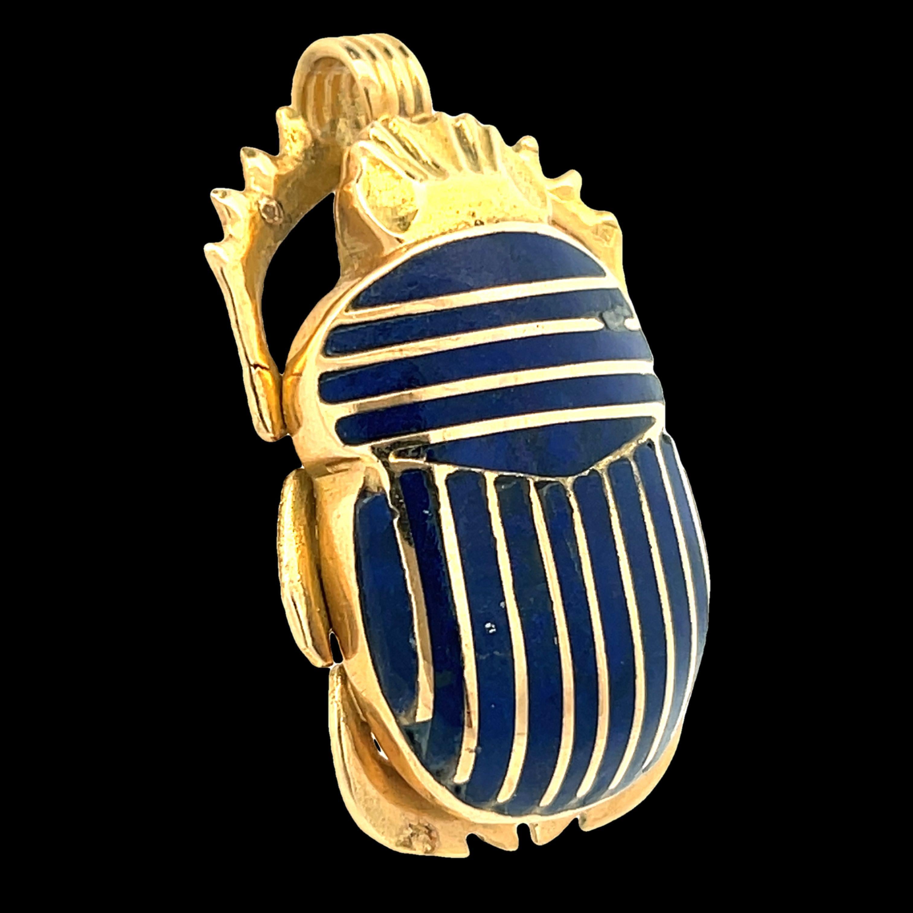 Ce magnifique pendentif en forme de scarabée égyptien est réalisé en or jaune 18 carats avec des bandes de lapis bleu insérées ou incrustées. Le lapis inséré a une riche couleur bleue qui s'associe magnifiquement à l'or jaune 18 carats riche en