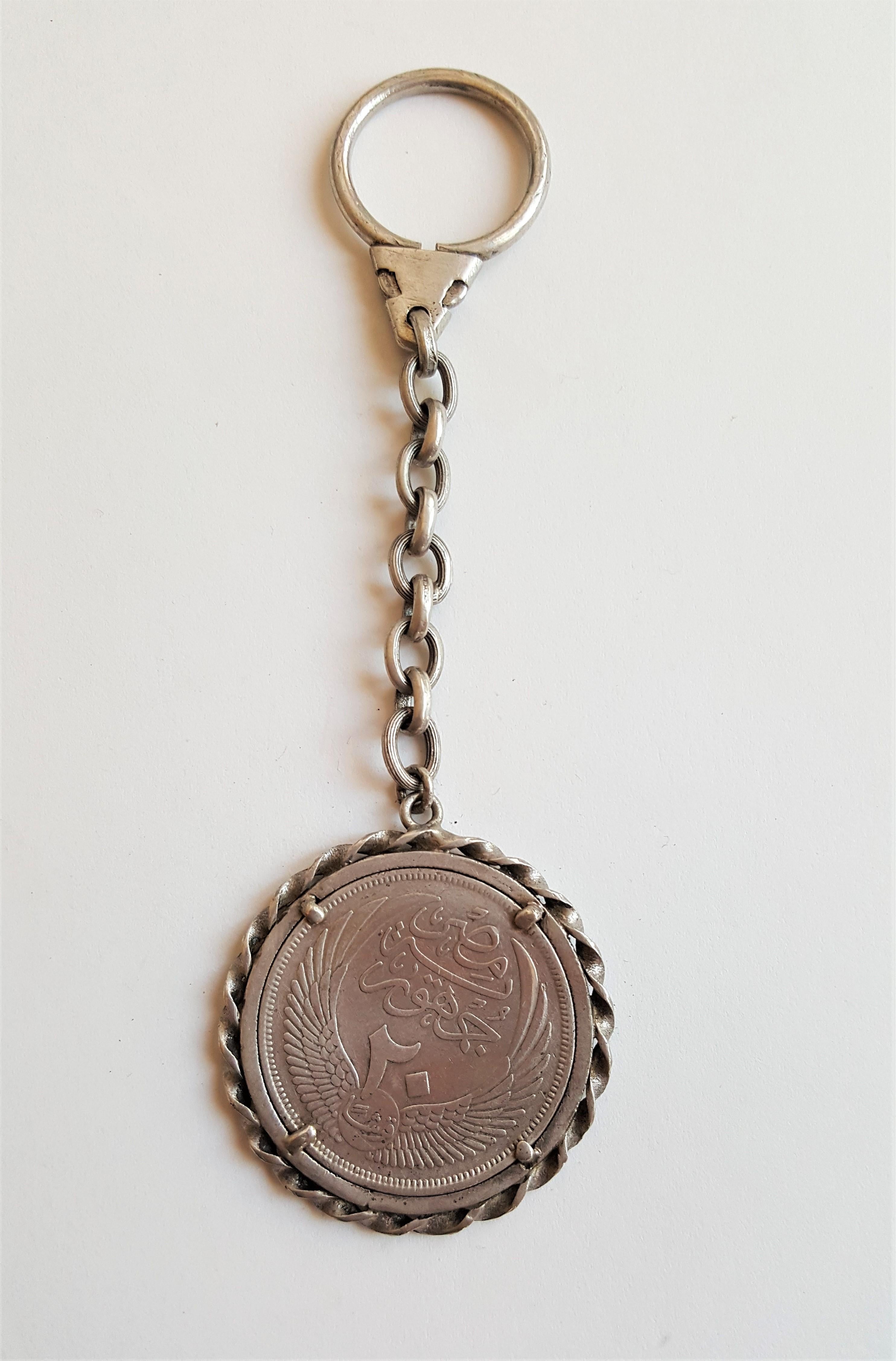 Unique silver keychain with a twisted bezel holding an Egyptian 1956 20 Piastres Silver Coin. The diameter is 40mm and the total length is 5 inches. The key chain weighs a total of 29.1 grams. The coin is in very nice condition and would make a nice
