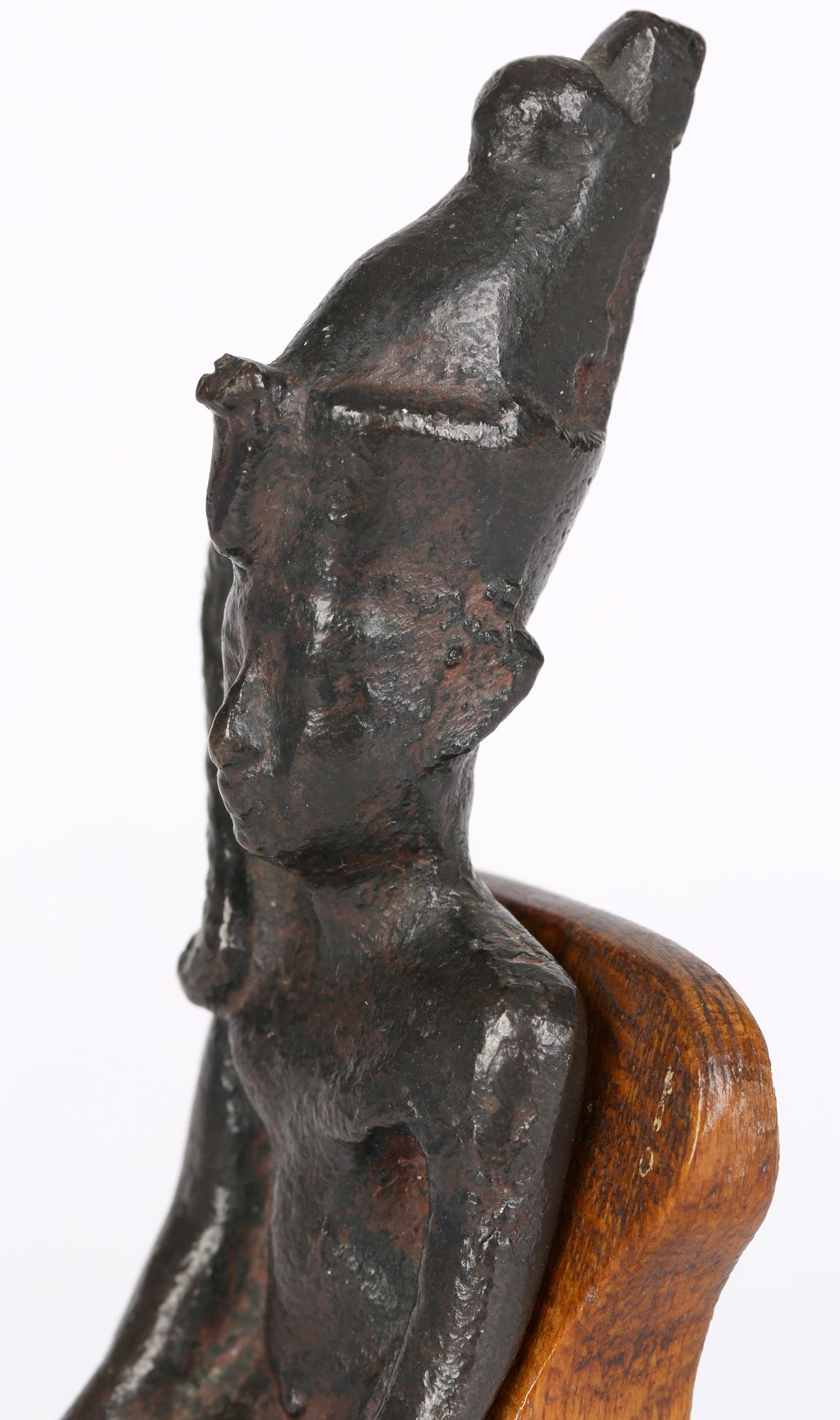 An interesting and unusual Egyptian bronze seated figure portraying the youthful god Harpokrates (Horus the child). The figure sits unclothed with legs bent and both arms resting by his sides. His face is indistinctly molded with a wide nose and
