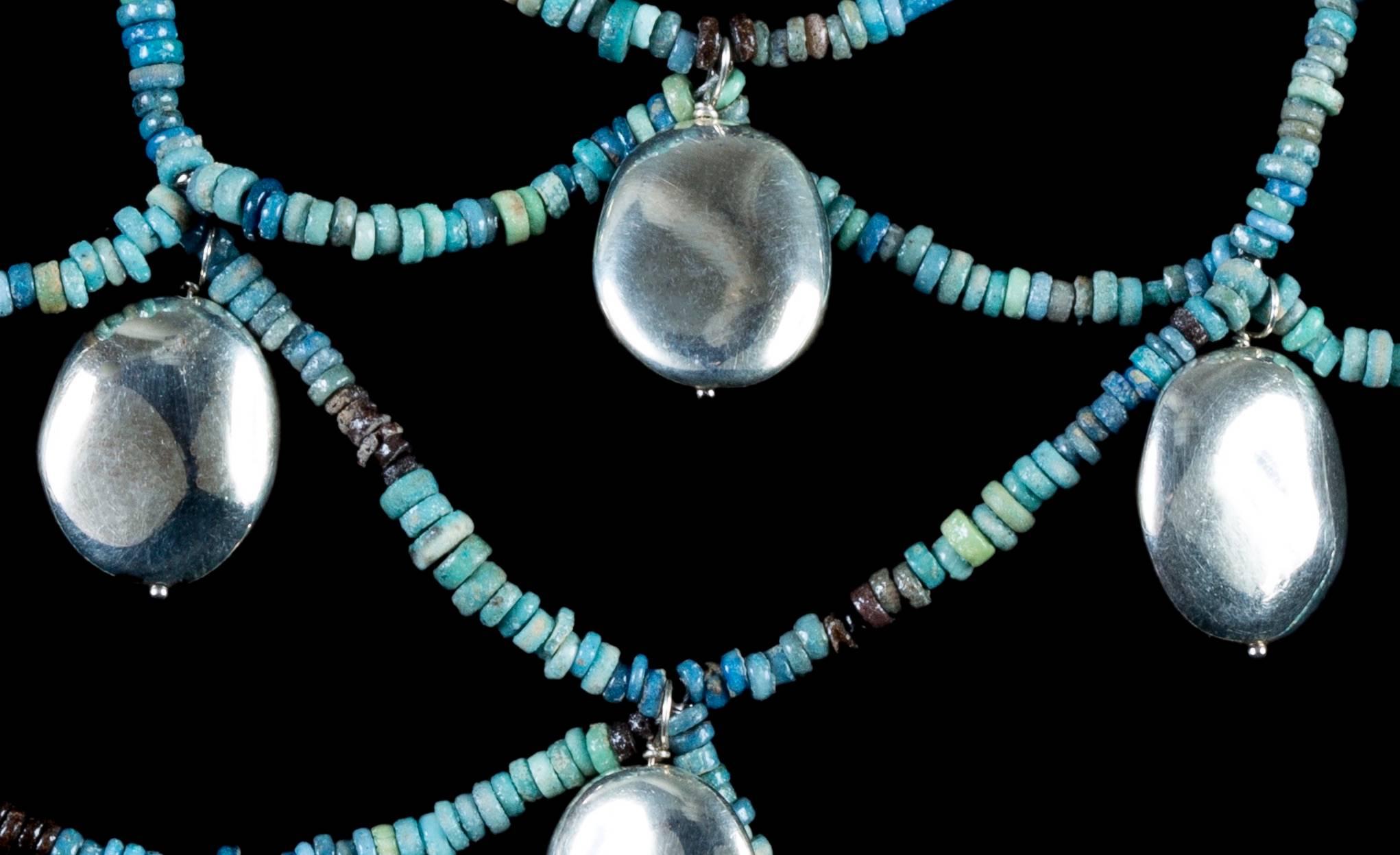 Silver bangles peek between the hollows of this woven necklace boasting stand upon strand of authentic Egyptian beads (Ca. 712-343 BC). Modern new string and clasp.

This piece comes from our 