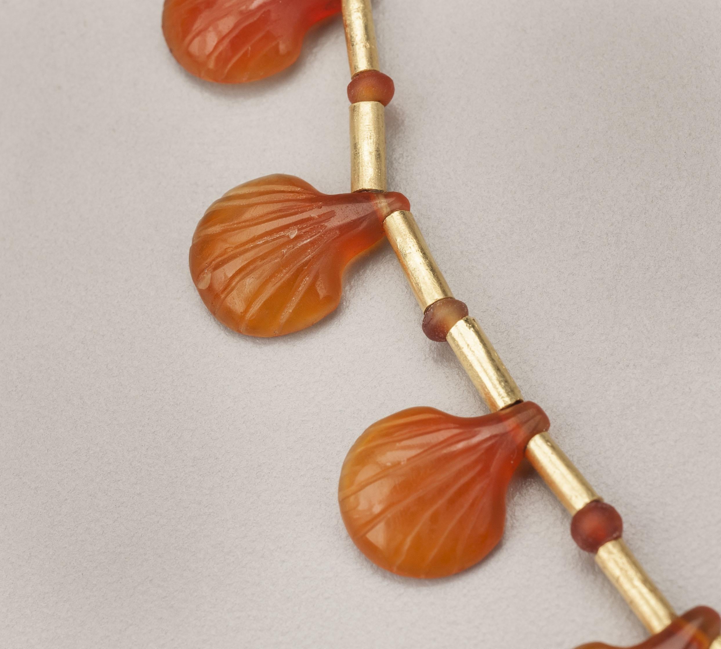 Twenty-three carnelian shells faced with cylindrical gold tube beads alternating with small carnelian beads. A set of gold beading tips and a hook and eye clasp complete the necklace. The shell pendants are ancient Egyptian and said to be from Tel