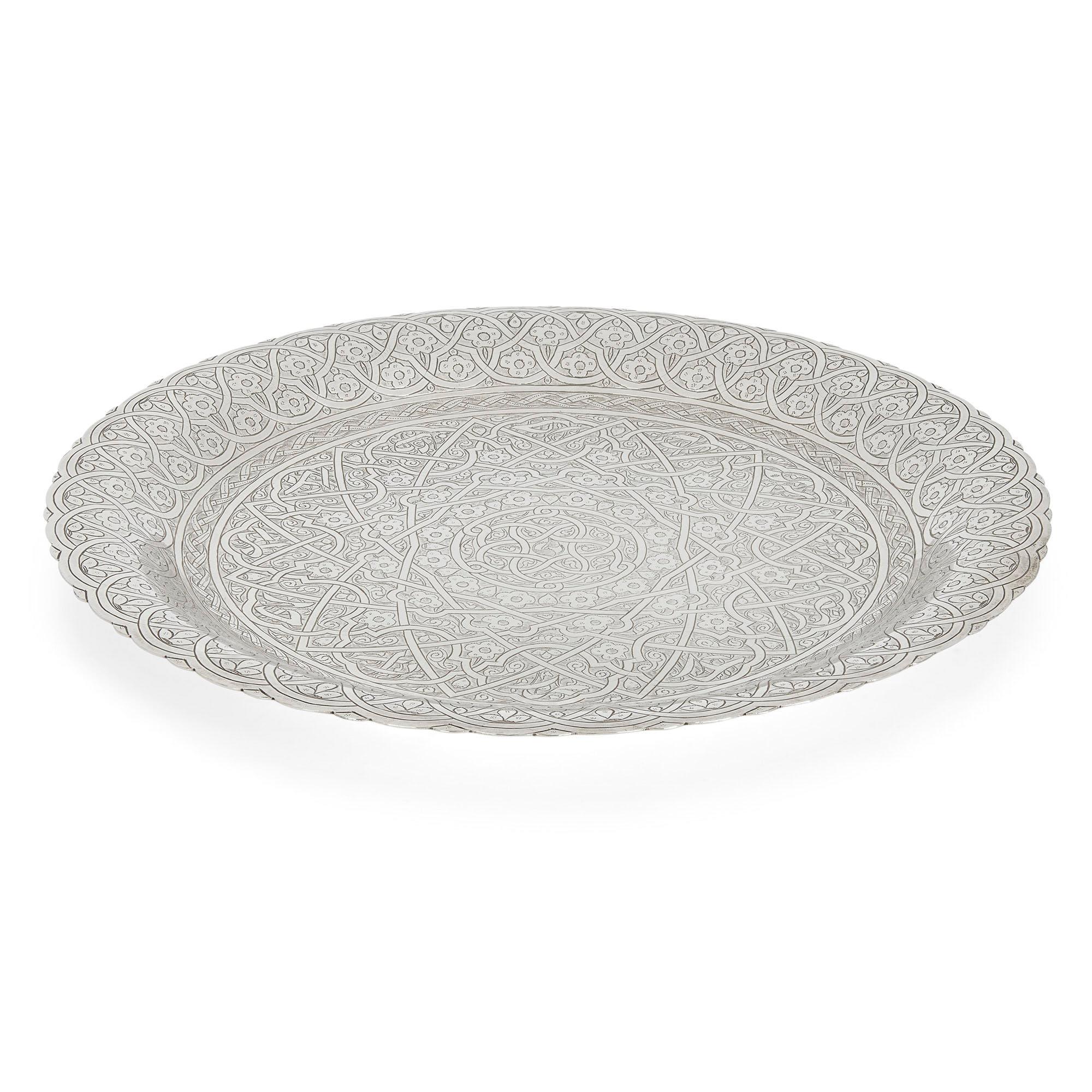 Egyptian engraved silver dish
Egyptian, 1959-1961
Measures: Height 2cm, diameter 28.5cm

This fine, elegant bowl is wrought from silver, and features floral and geometric engravings all over, as well as a stepped rim and petal edge.

The