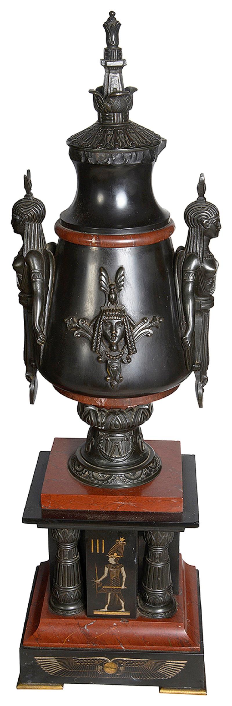 A very imposing 19th Century Egyptian influenced mantle clock garniture, the black and rouge marble having wonderful patinated bronze mounts depicting Egyptian sphinx like mounts to the clock and side pieces, the gilded clock face with an eight day