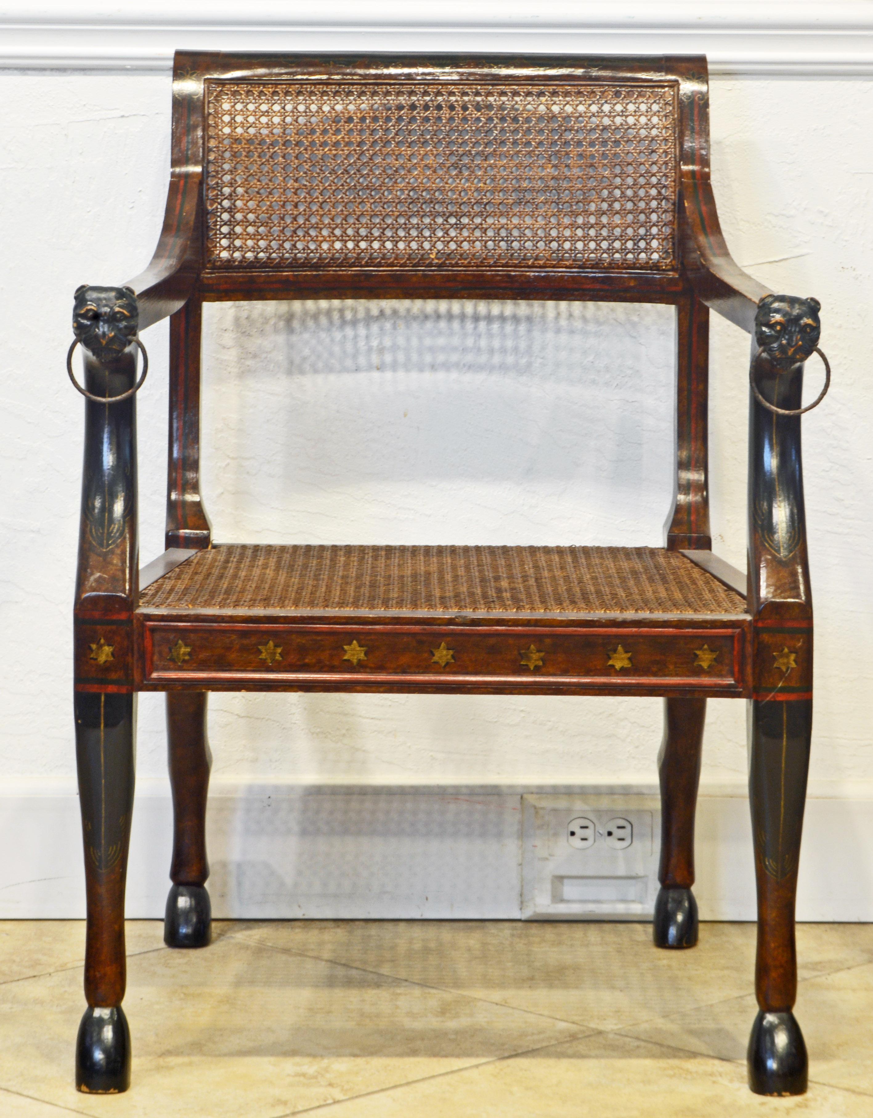 Of generous proportions this unique Italian Egyptian Revival armchair features caned seat and backrest in a frame carved with hoof footed animal legs, stylized lion's heads fronting the arm rests and decorated with paint in the Venetian manner. The