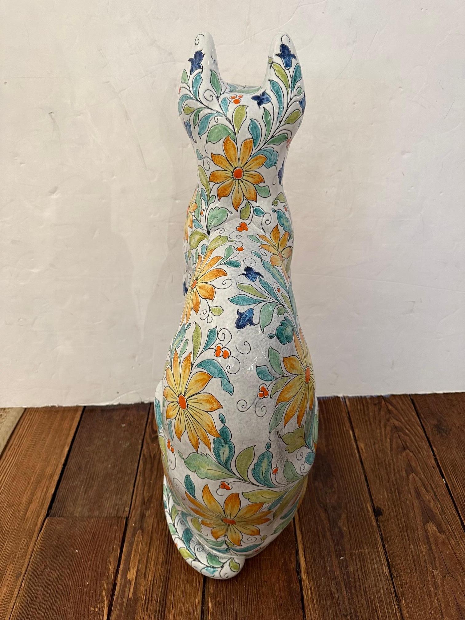 Large striking Italian Egyptian inspired terracotta statue of a beautifully glazed and decorated cat with floral designs with green, turquoise, yellow and orange against a white background. It dates to the late 20th century and is a fine