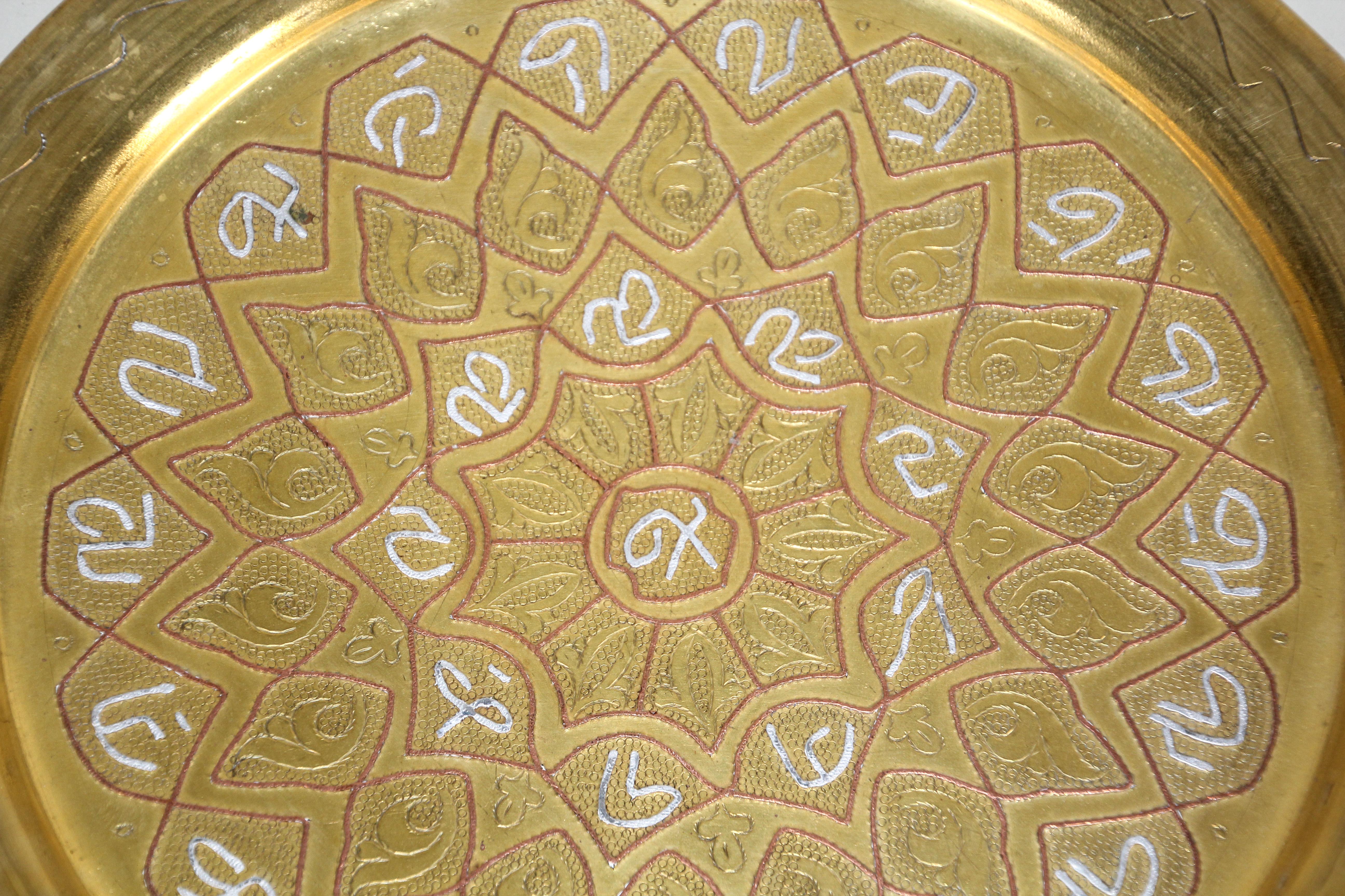 Islamic Arabic calligraphy circular tray with silver overlay.
Round Egyptian brass tray overlaid with metal silver and copper Islamic calligraphy writing and foliates patterns.
This Middle Eastern Egyptian collector metal brass tray is first