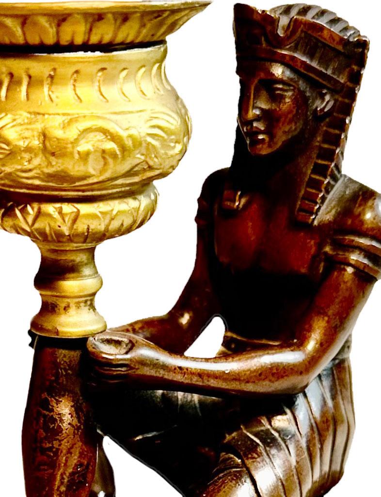 This is a neoclassical candlestick made into a lamp with a slate base, dore bronze  and the Egyptian is patinated in a dark color. It has a new cord. Lamp Shade is older, but in good condition for its age. The statue its self measures five inches,