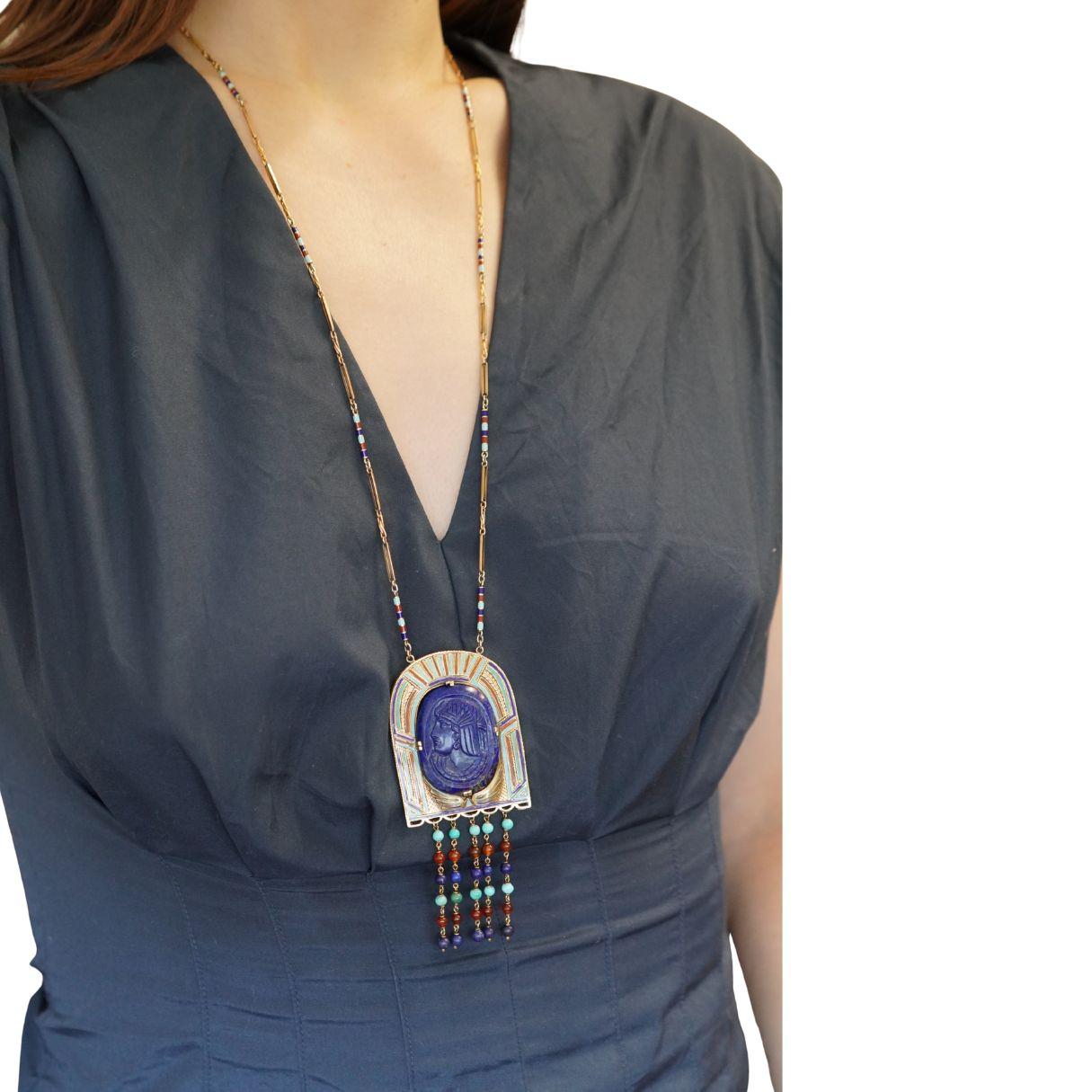 Magnifico esempio di design Art Deco Egyptian Revival, questa collana del 1925 circa cattura il fascino dell'antico simbolismo attraverso un'impeccabile maestria e un colore deciso. Il centro è caratterizzato da una placca di lapislazzuli finemente