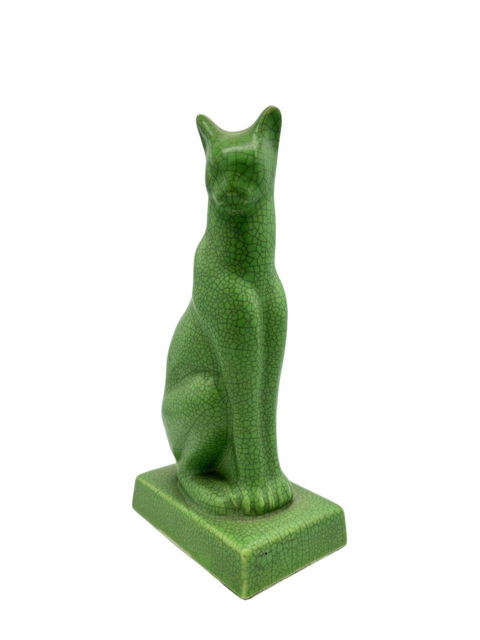 This 9-inch ceramic Bastet cat embodies the Post-War Egyptian Revival style, characterized by its sleek and stylized depiction of the ancient Egyptian feline deity. The cat, inspired by the revered goddess Bastet, exudes an aura of mystique and