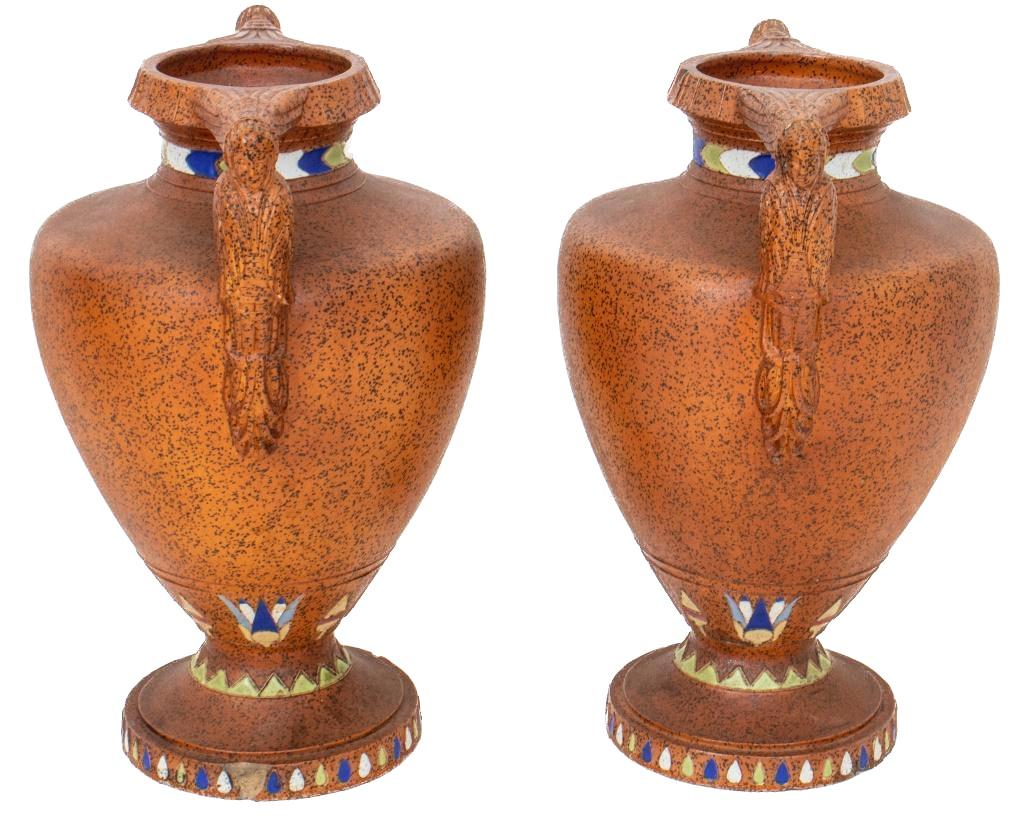 Egyptian revival Art Deco style faux porphyry hand decorated pair two handled decorative piece / vase. Each vase features a pharaonic figure winged handles , with the neck decorated with green, cobalt, and white glazes, resting on a round socles